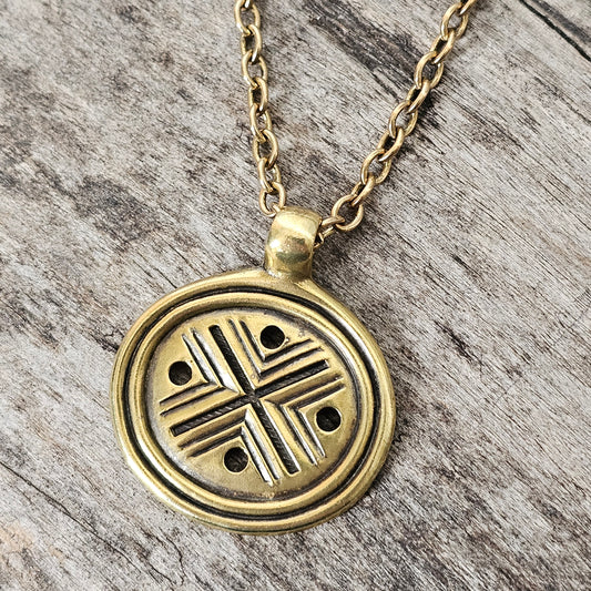 Gold-toned pendant necklace featuring a circular design with a cross-like pattern.