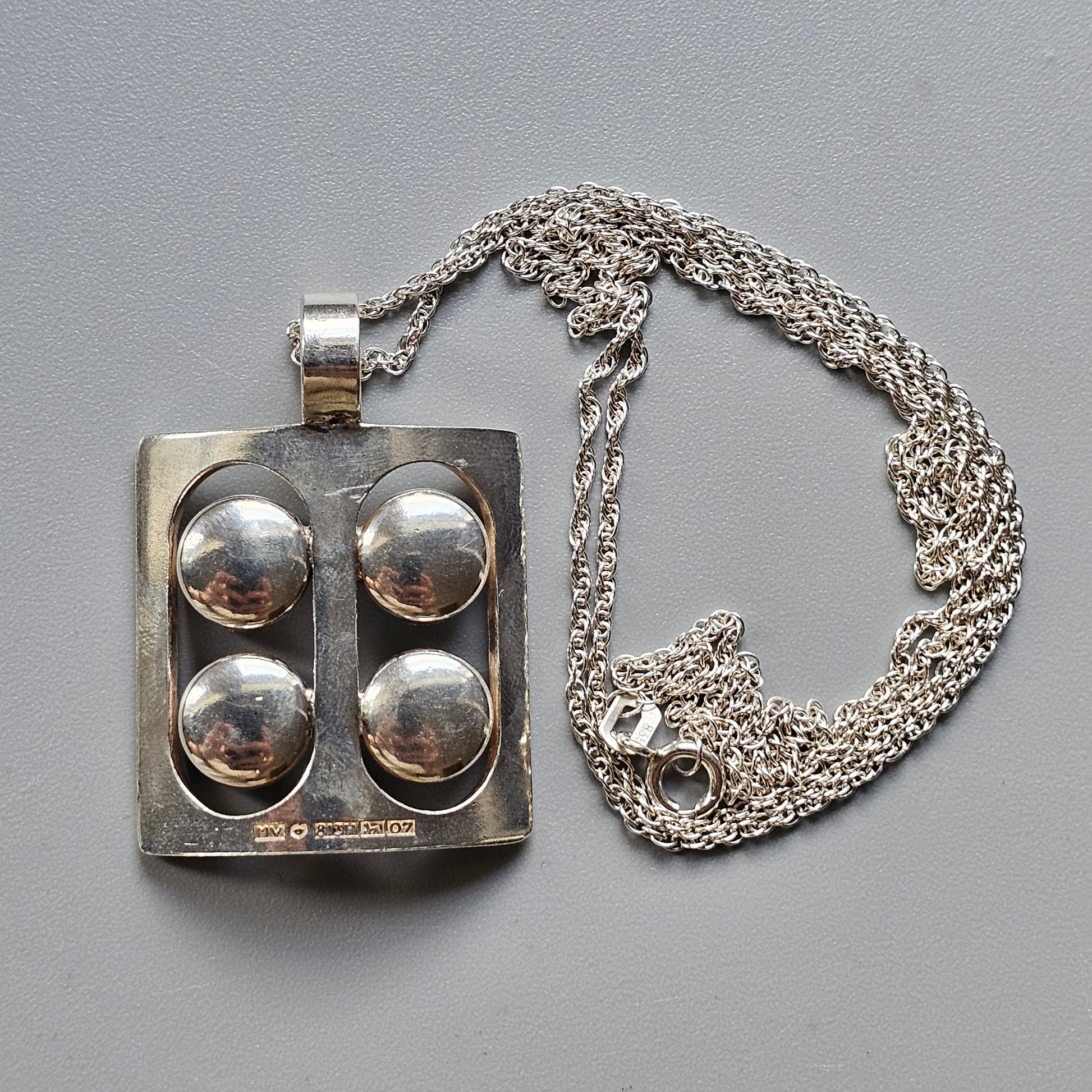 Silver pendant with four circular convex elements attached to a chain necklace.