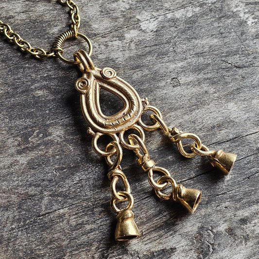 Ornate gold-toned pendant necklace with three small bell-shaped charms hanging from a decorative loop.