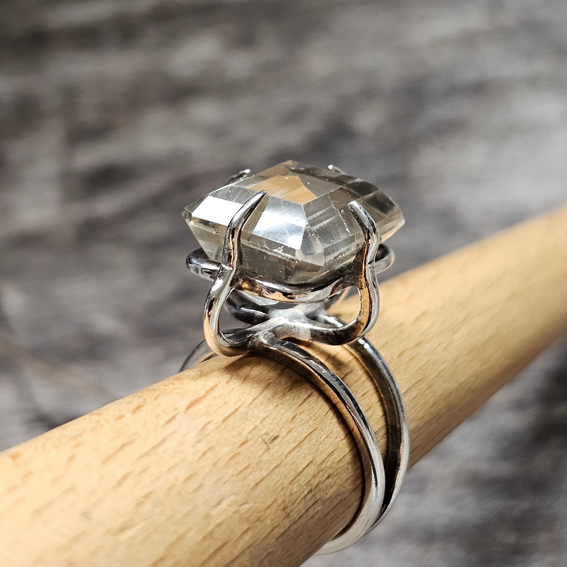 Silver ring with a clear, faceted gemstone in an intricate setting.