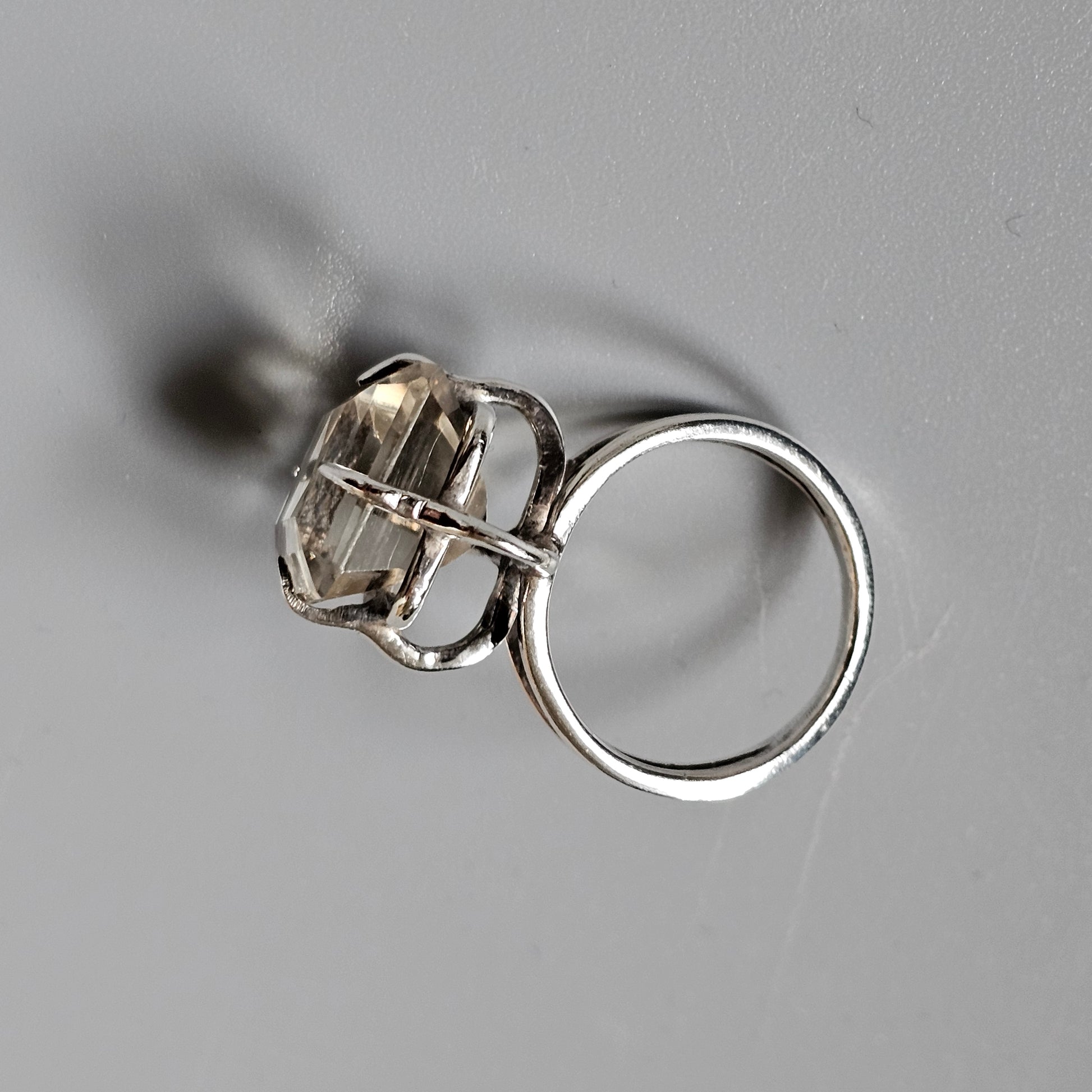 Silver ring with a clear gemstone in a prong setting.