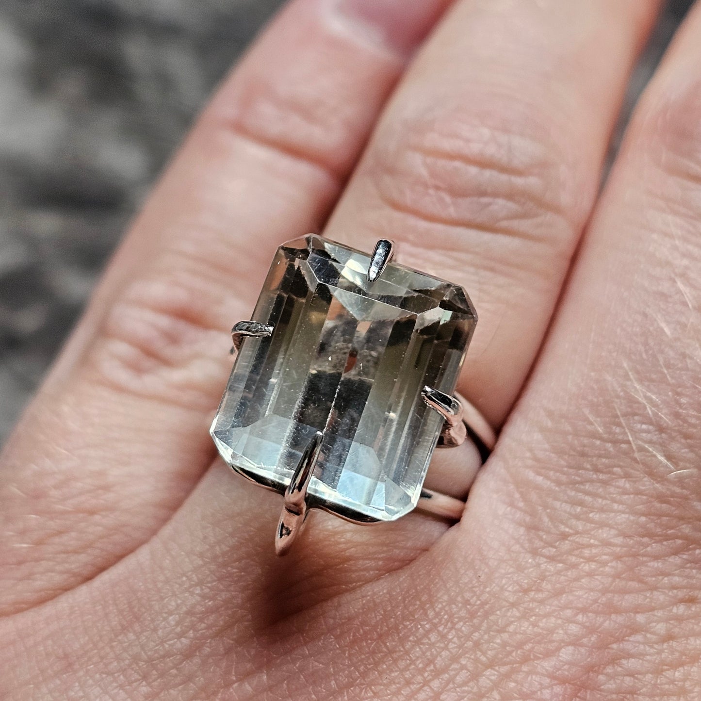 Rectangular gemstone ring with a clear or pale-colored stone in a prong setting.