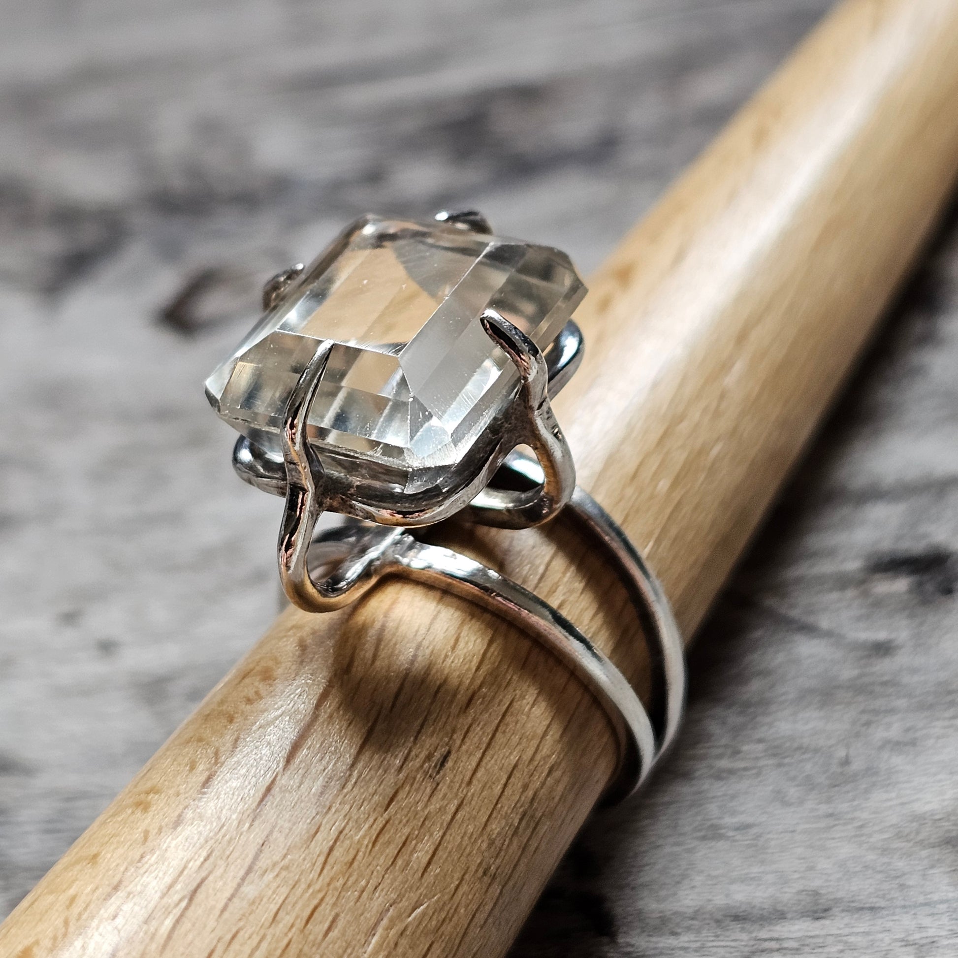 Silver ring with a prominent clear gemstone in a prong setting.