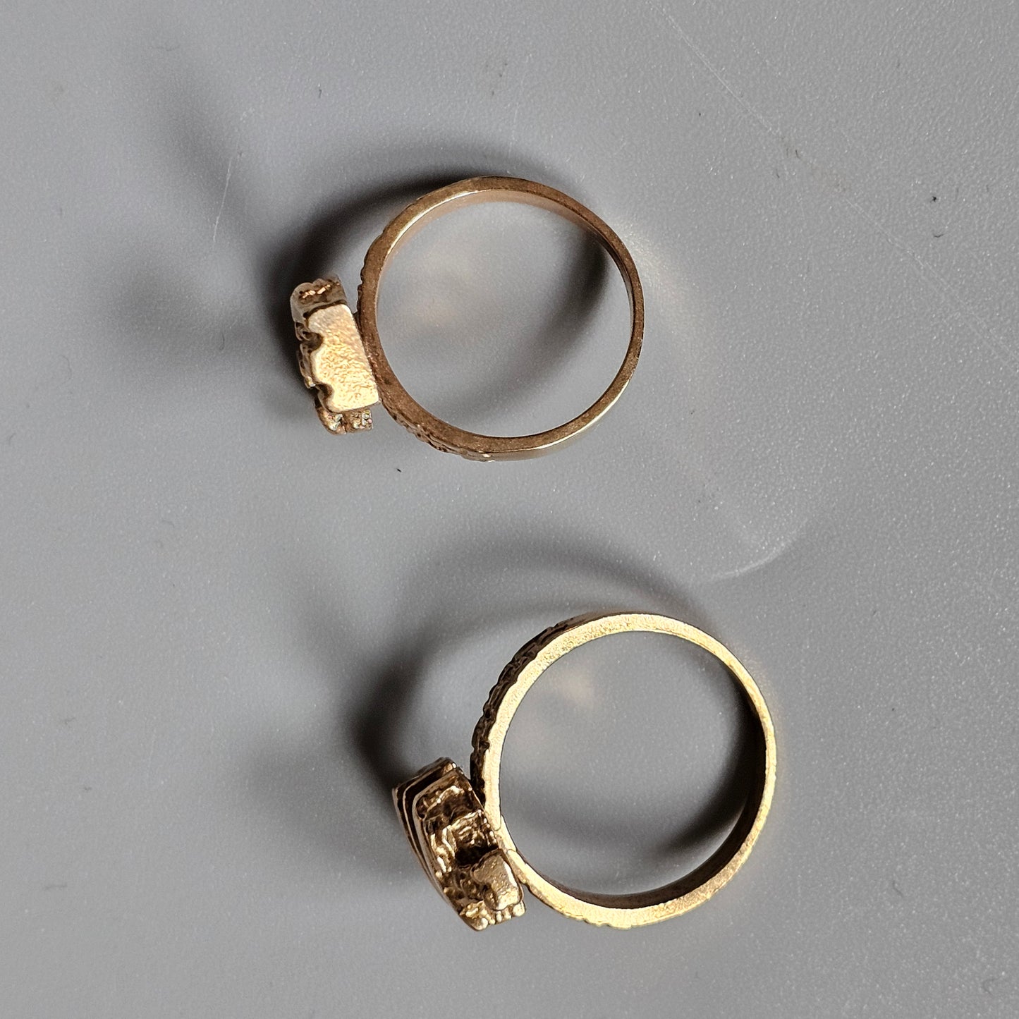 Two rings with decorative elements on their bands, one gold-colored and one silver-toned.