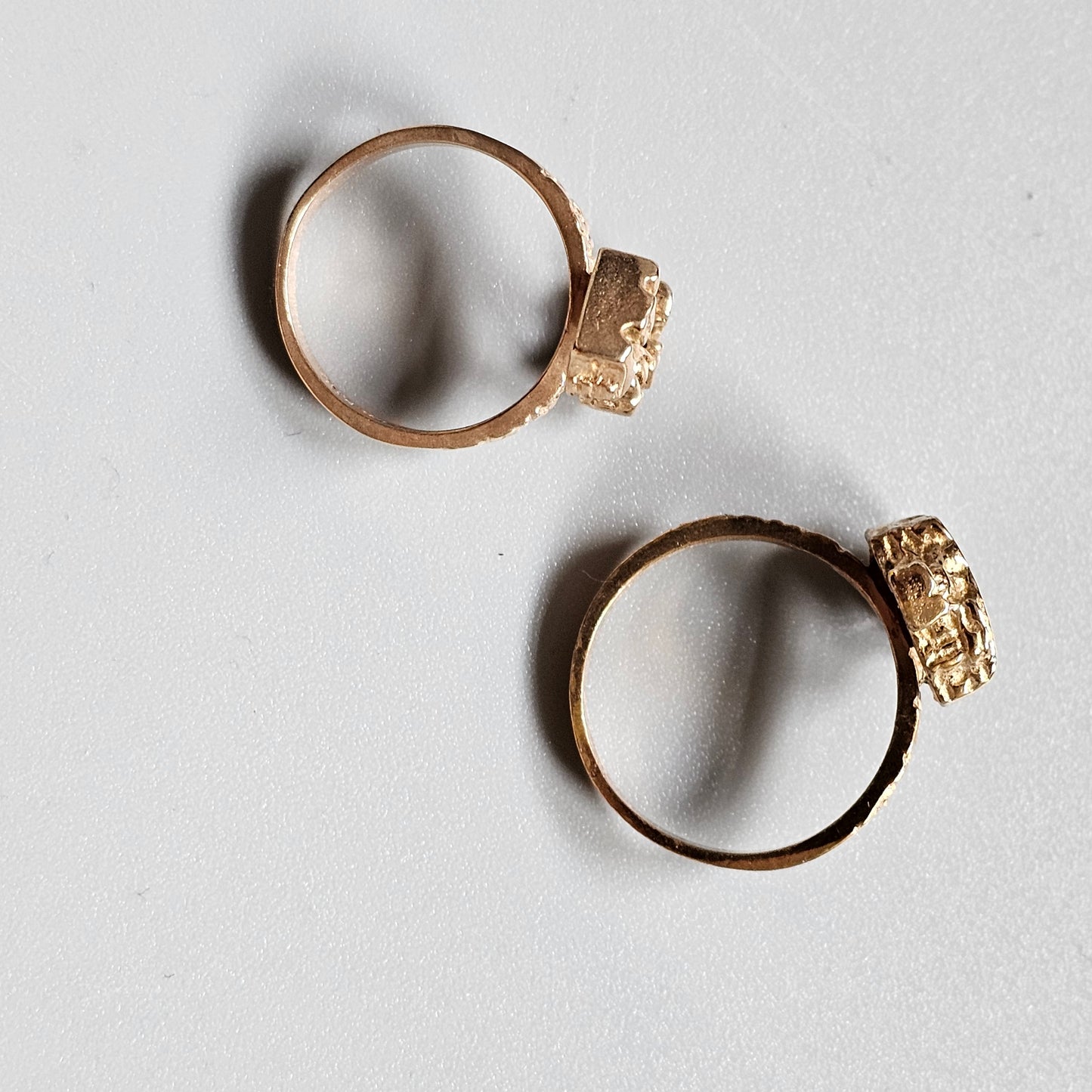 Two gold rings with textured, nugget-like settings.