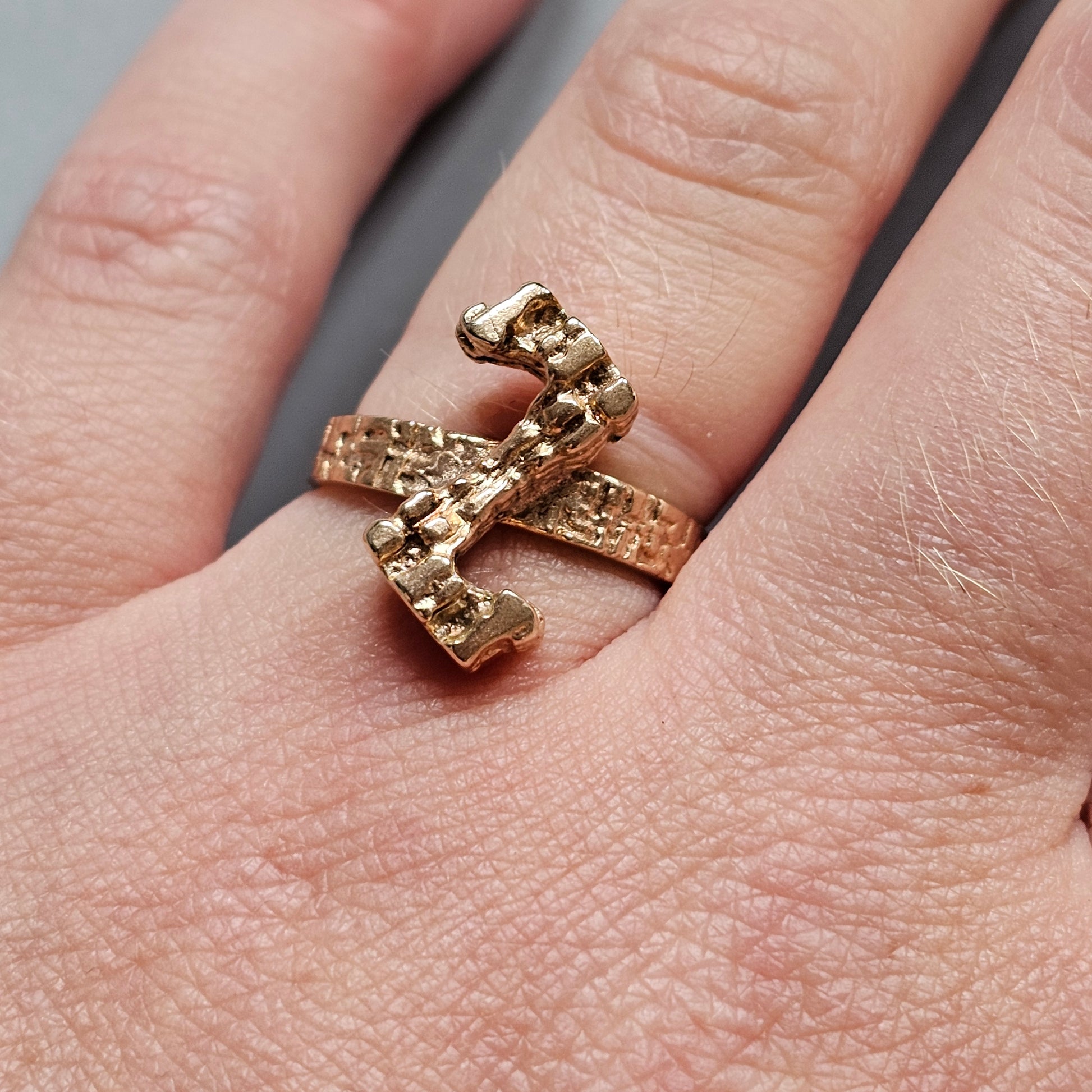 Gold ring shaped like a lightning bolt or zigzag pattern worn on a finger.