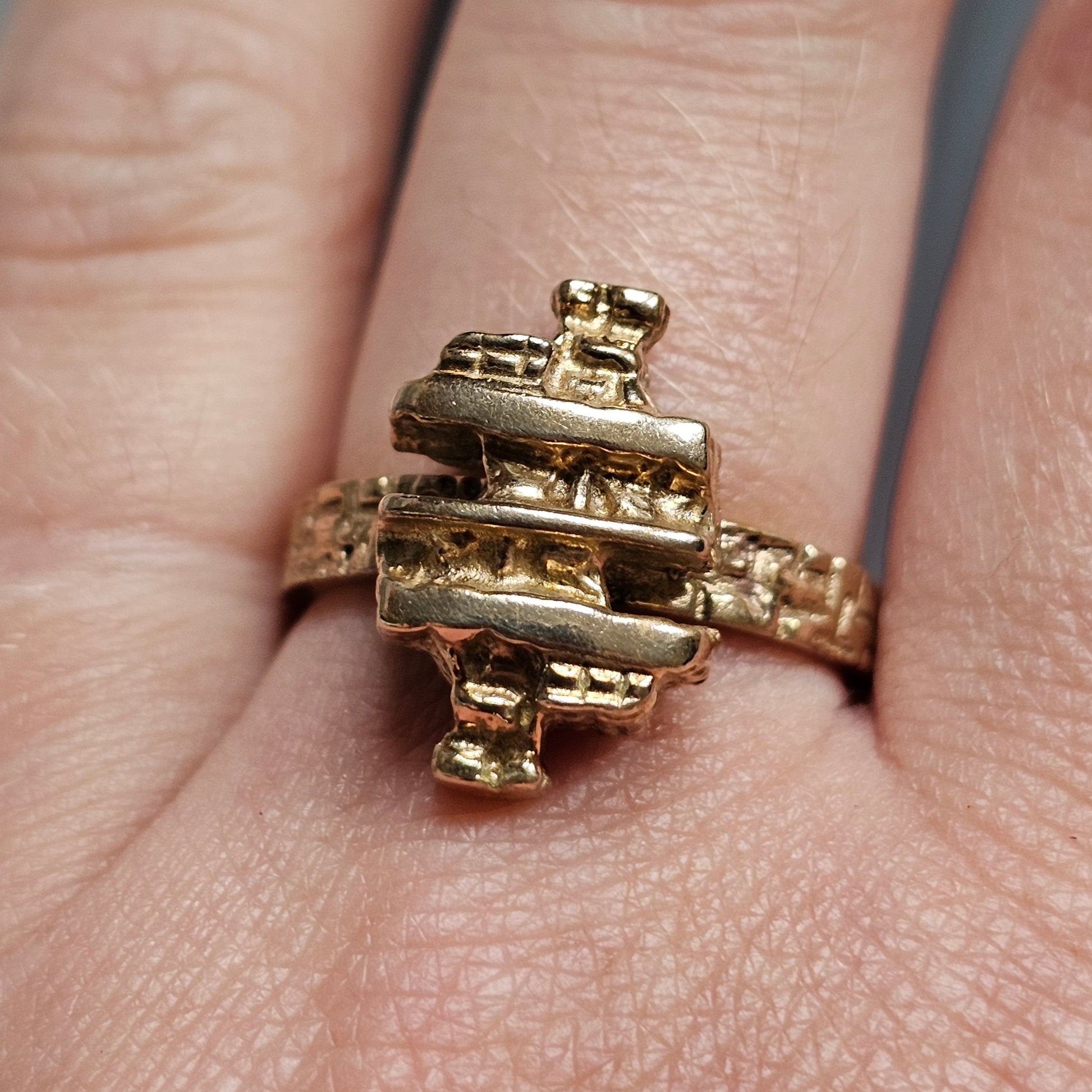 Gold ring with an unusual geometric design resembling stacked bars or blocks.