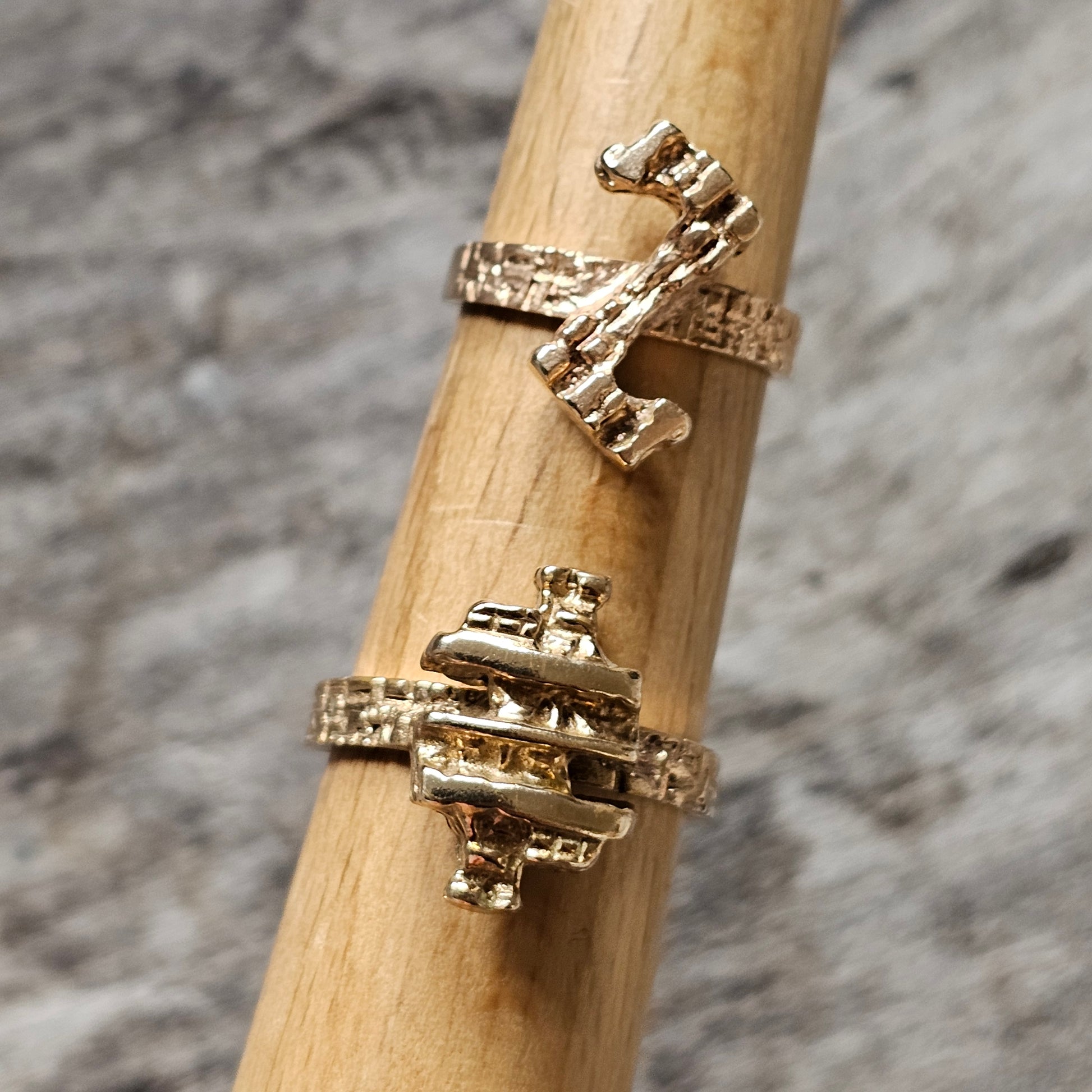 Gold-colored ring with a cross-shaped design and textured bands.