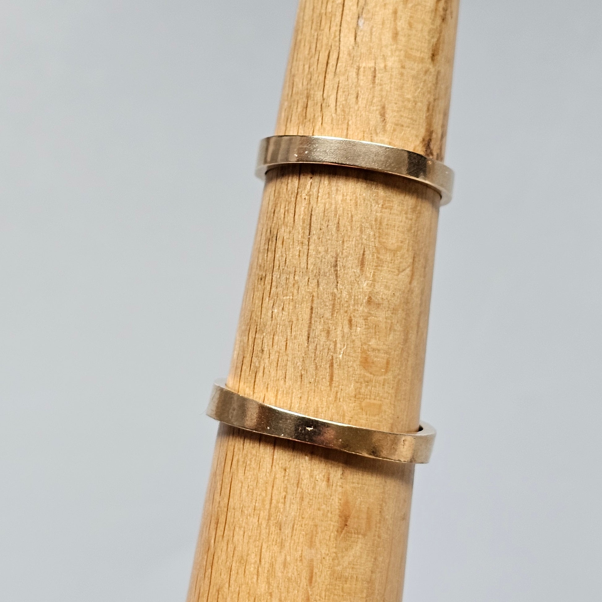 Two simple gold bands or rings placed on a wooden cylindrical object.