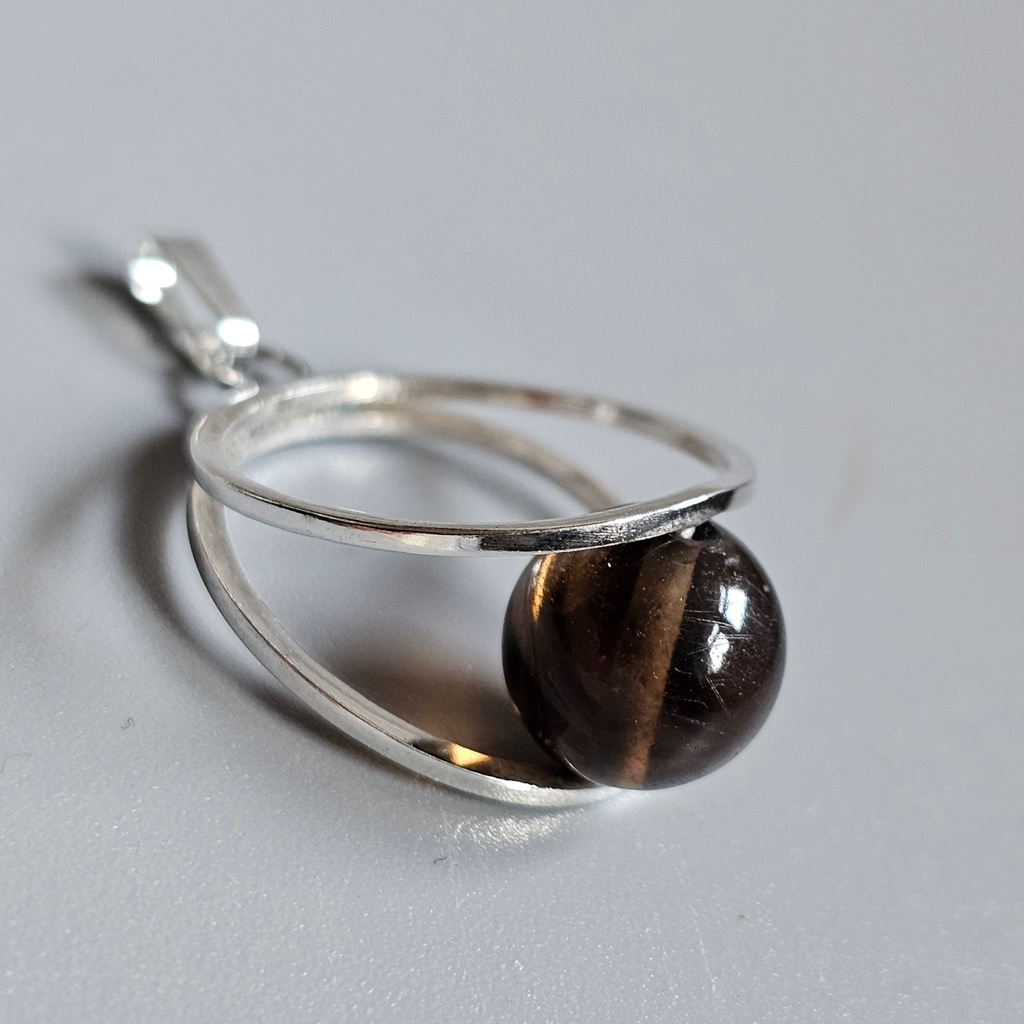 Silver pendant featuring a dark brown spherical gemstone or bead.