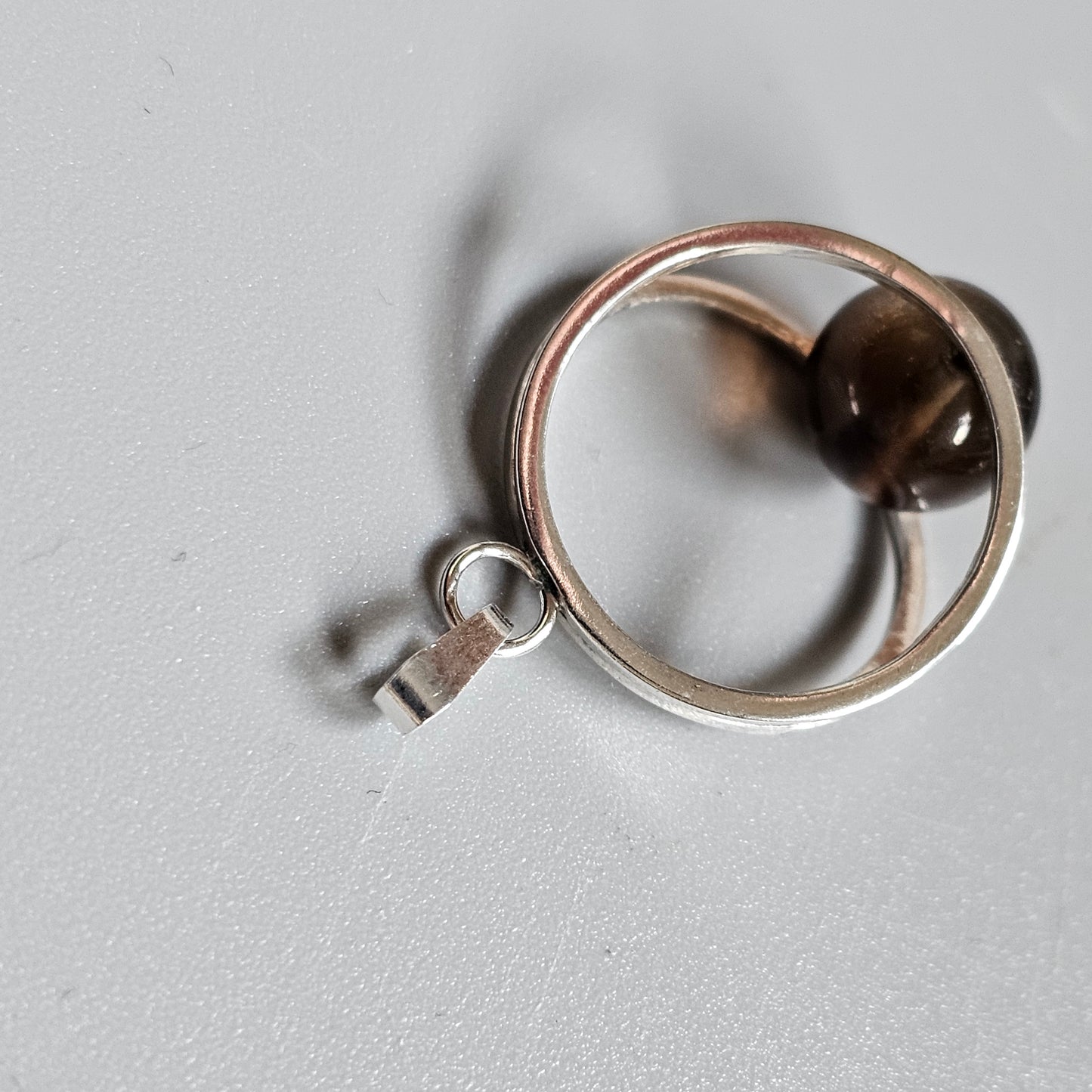 Silver ring with a small key charm attached.