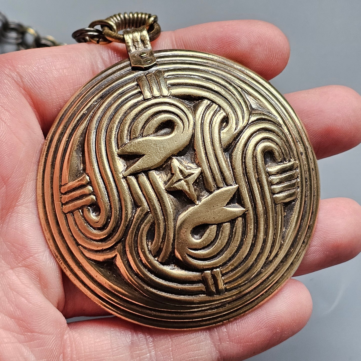 Ornate brass pocket watch with an intricate swirling design on its face.