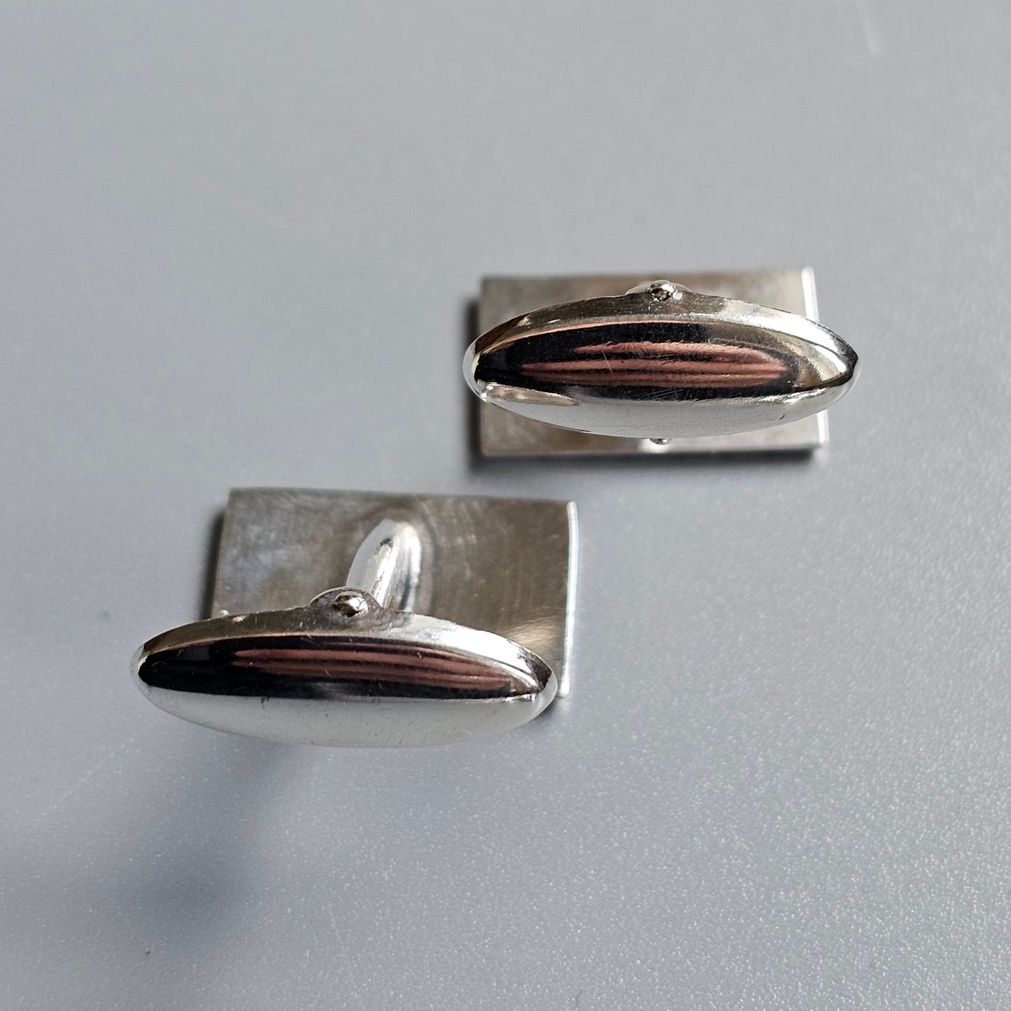 Pair of silver and copper cufflinks with oval-shaped designs.