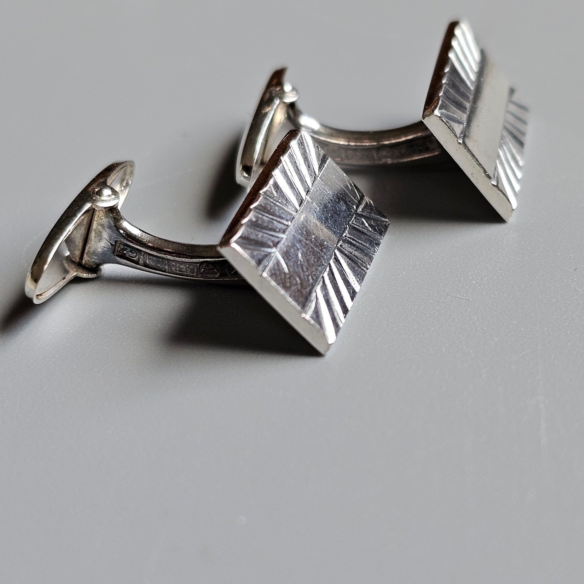 Pair of silver cufflinks with a textured square design.