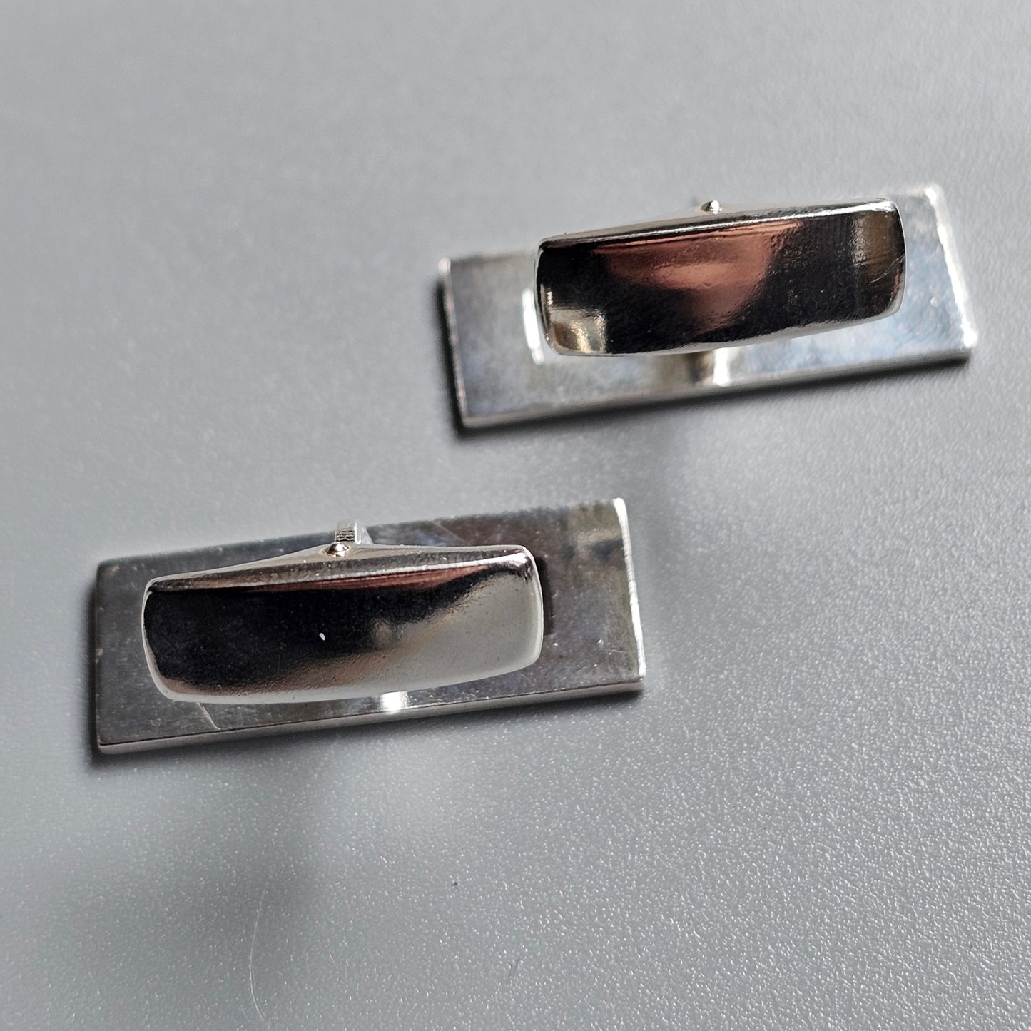 Pair of rectangular metal cufflinks with dark inlaid centers.