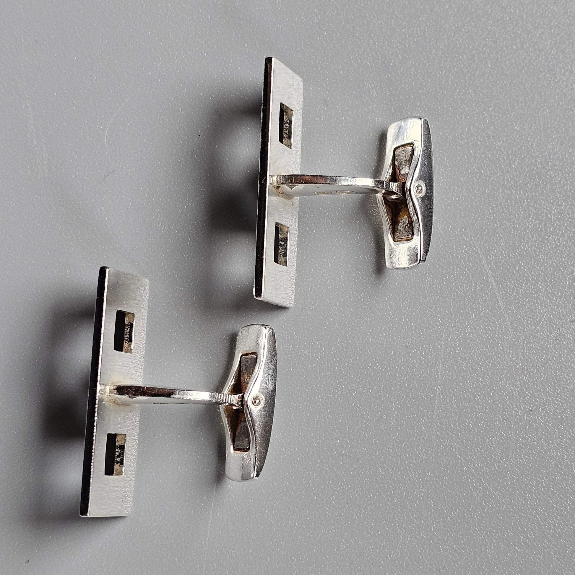 Pair of metal cufflinks with rectangular faces and toggle closures.