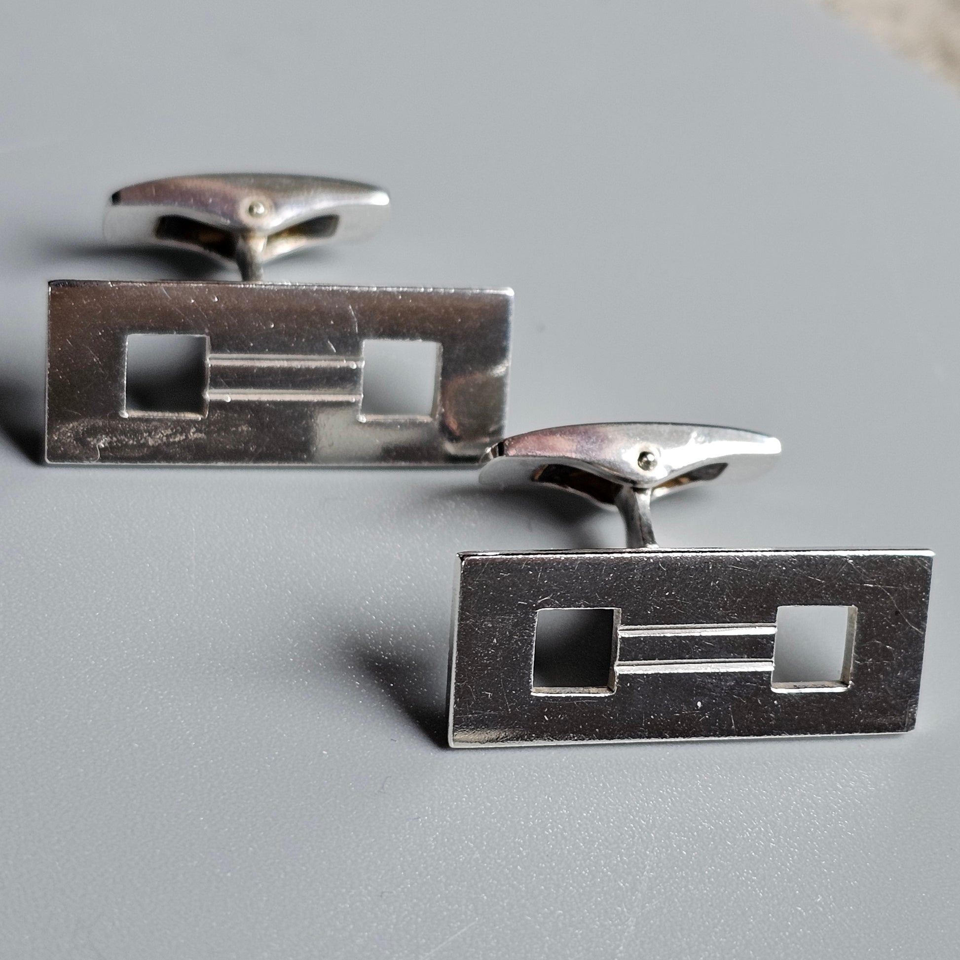 Pair of rectangular silver cufflinks with geometric cutout designs.