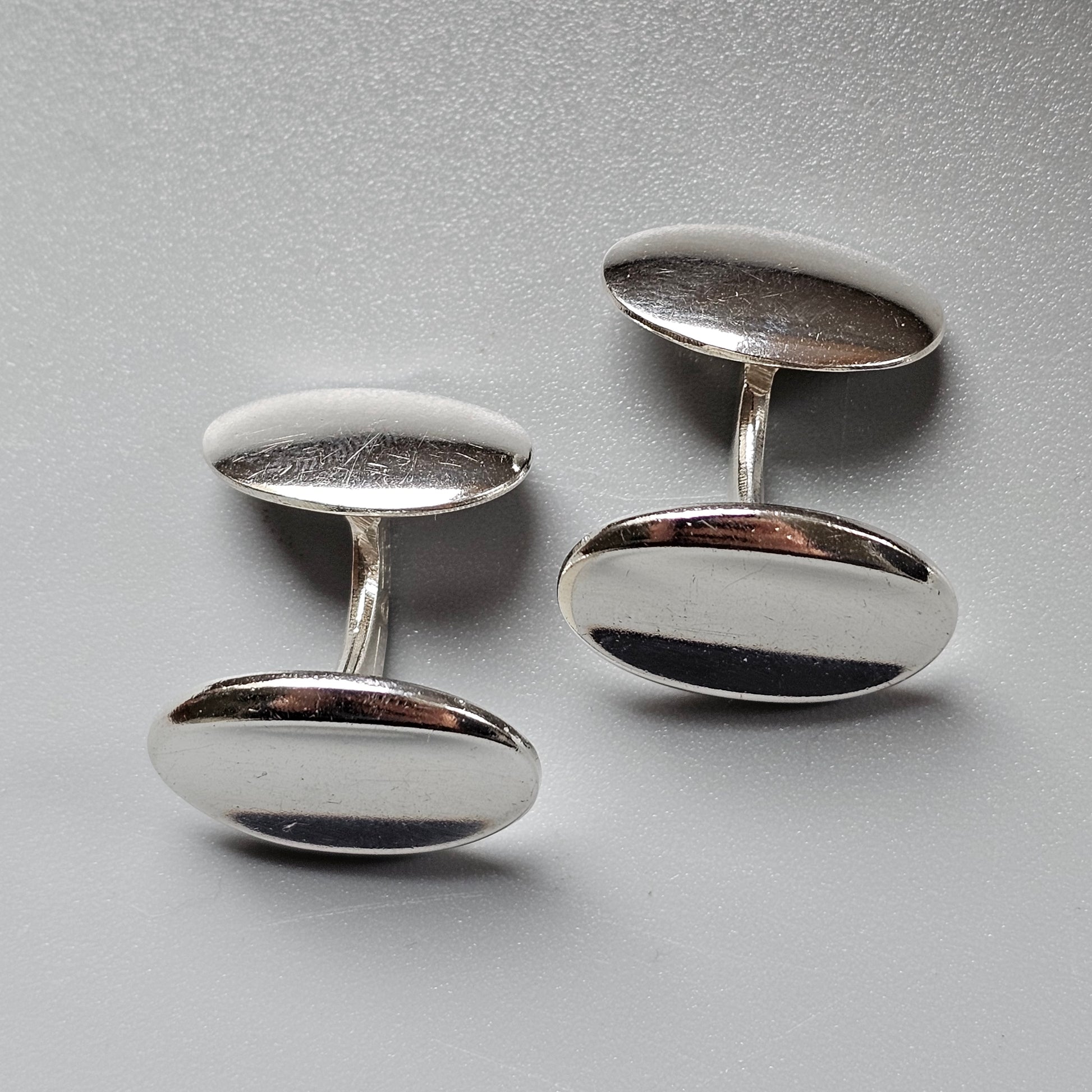 Pair of oval silver cufflinks with a two-tone design.