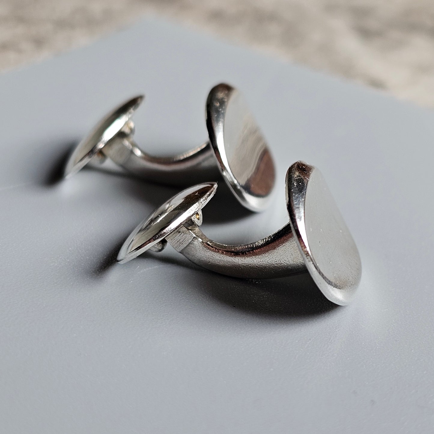 Pair of silver cufflinks with a curved, hook-like design.