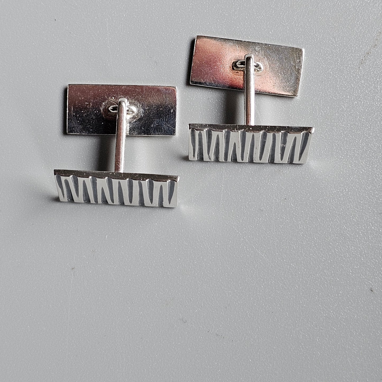 Pair of modernist cufflinks with rectangular tops and serrated bottom edges.