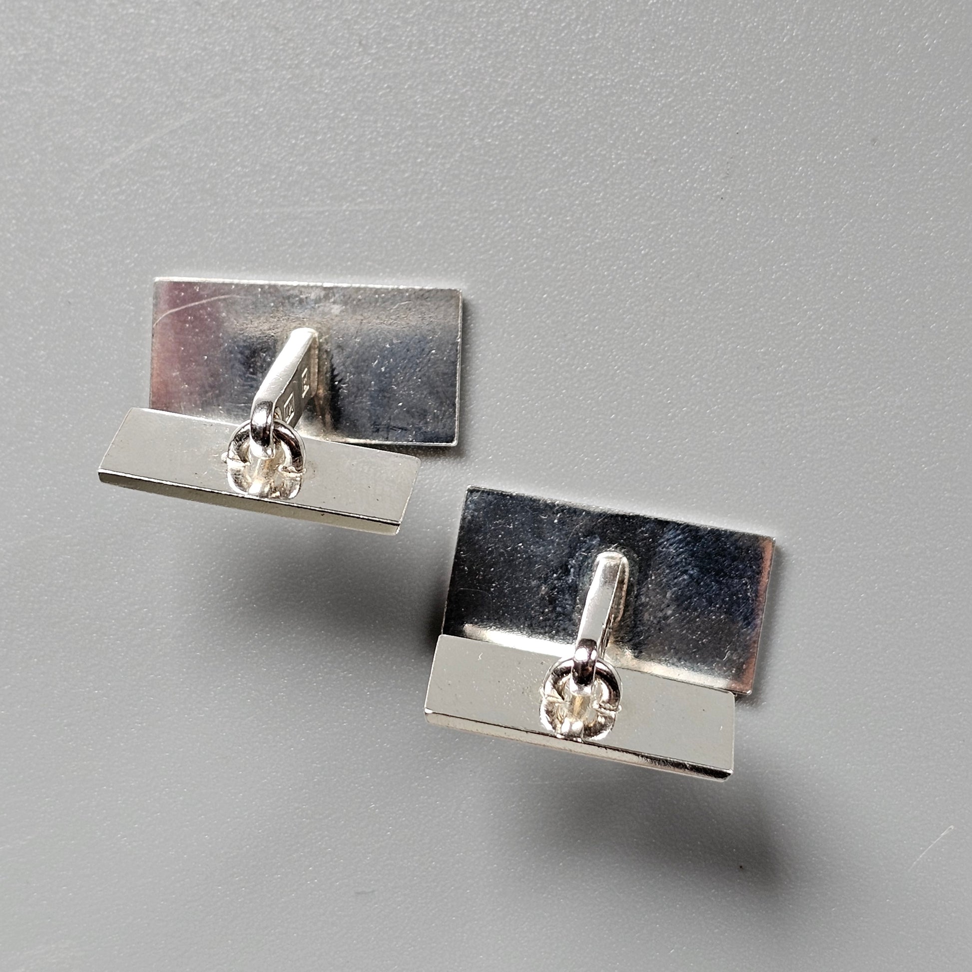 Pair of silver rectangular cufflinks with small crystal or diamond accents.