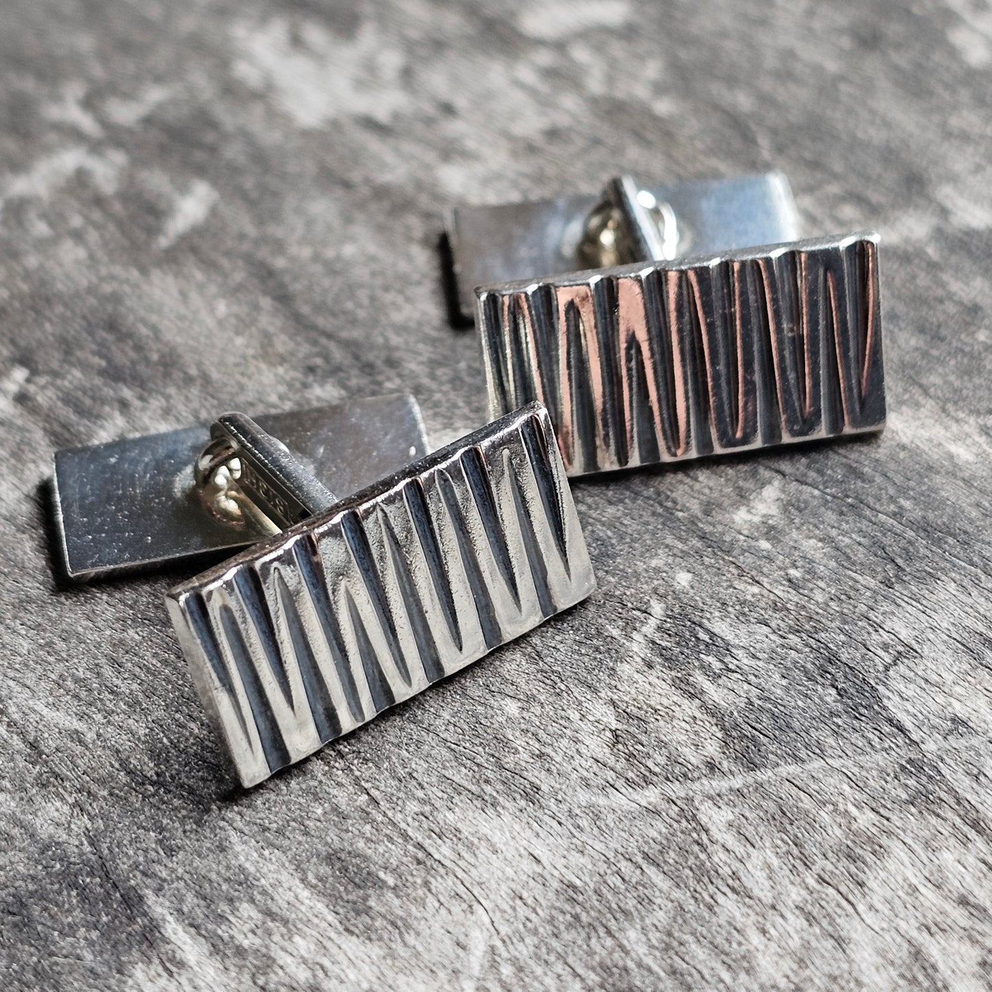 Pair of rectangular silver cufflinks with textured vertical lines.