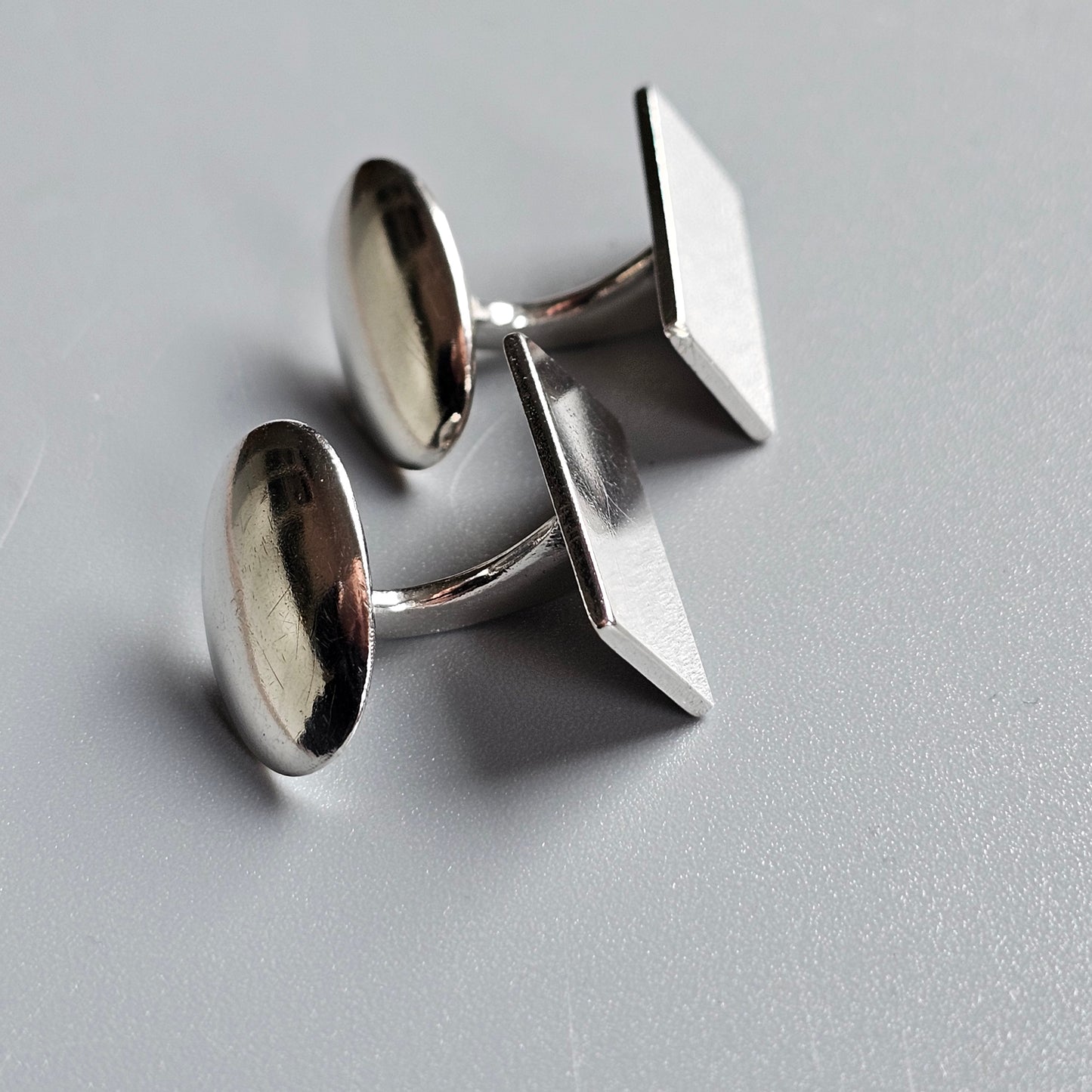 Pair of silver cufflinks with contrasting round and square ends.