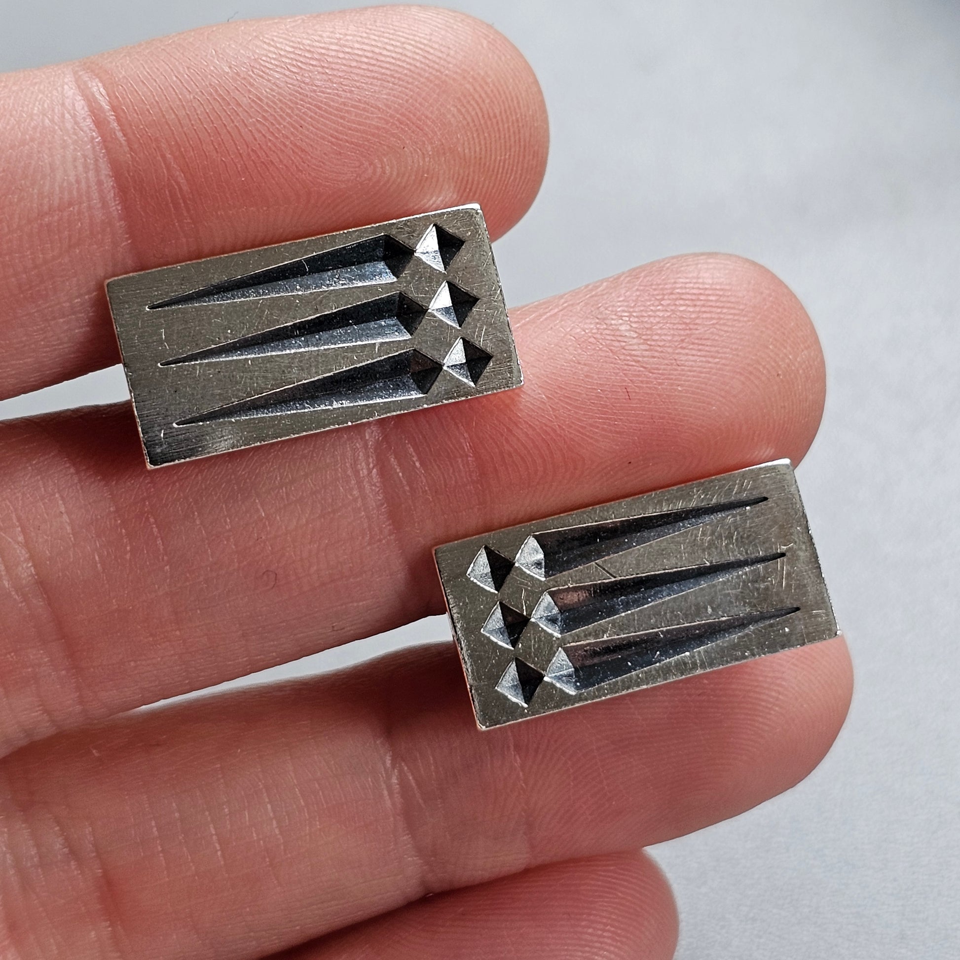 Metal cufflinks with a geometric pyramid design.