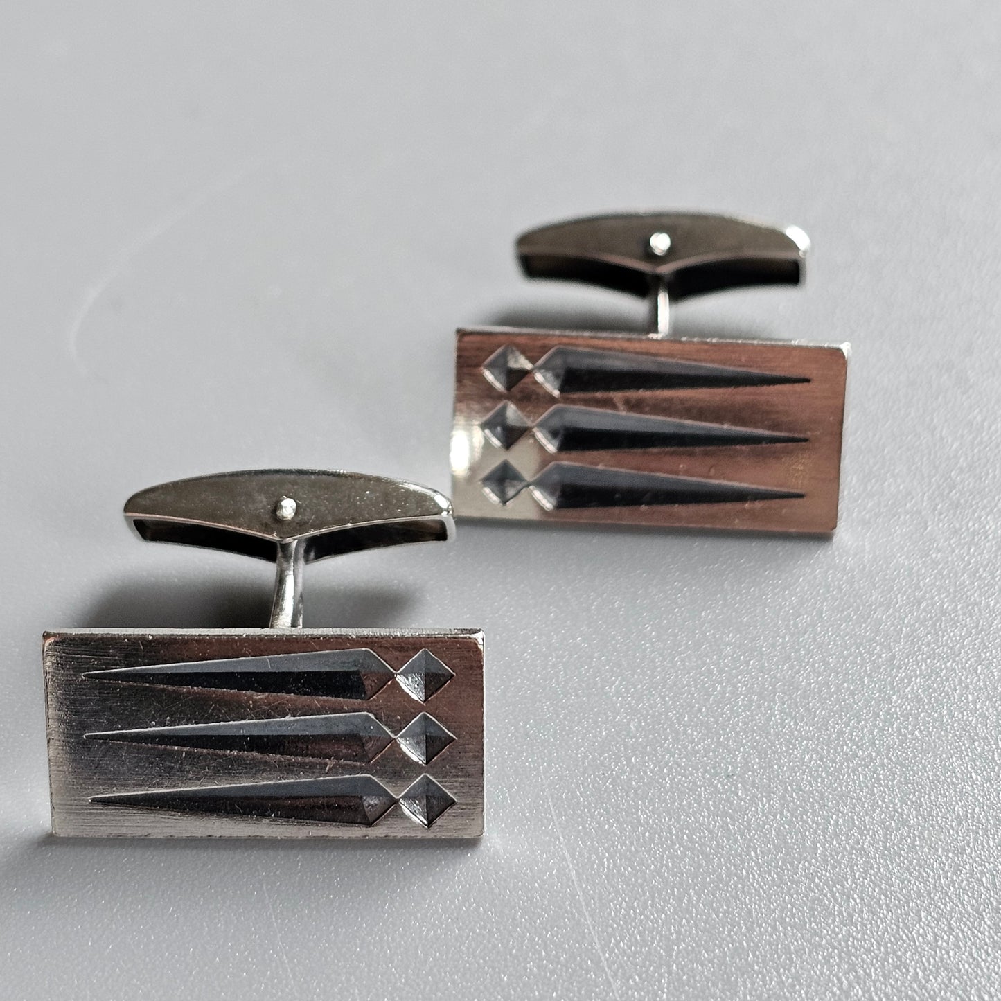 Pair of rectangular metal cufflinks with geometric designs.