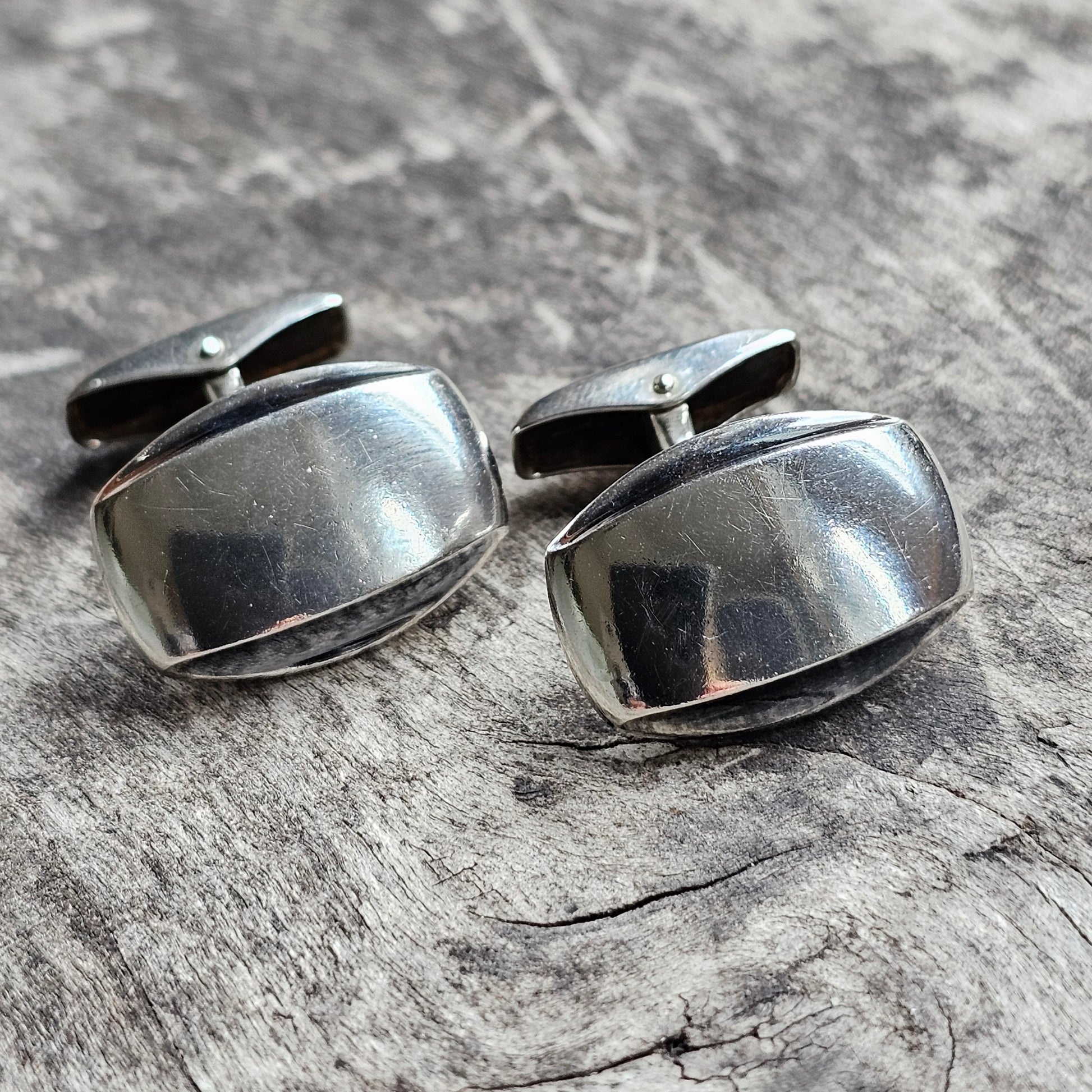 Pair of silver oval cufflinks with a smooth, reflective surface.