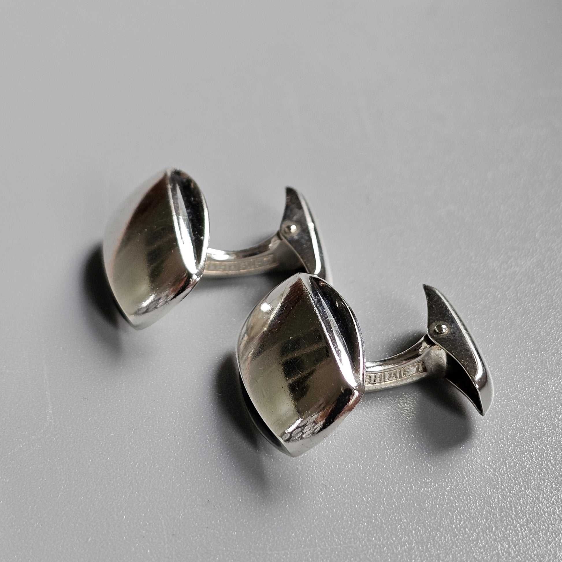 Pair of silver cufflinks with a square, slightly curved design.