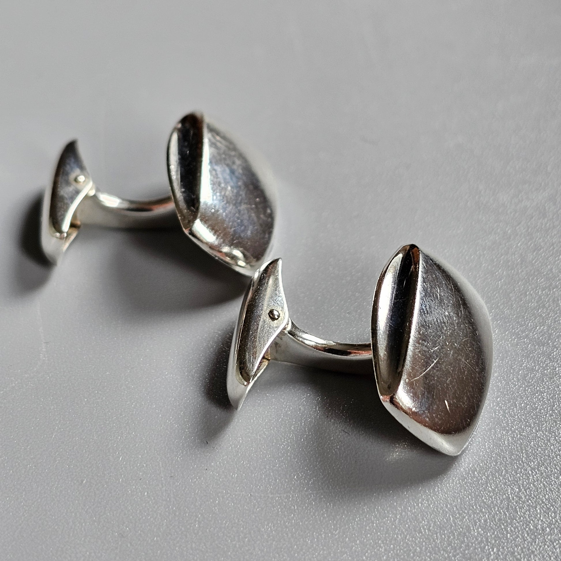 Pair of silver cufflinks with smooth, curved surfaces.