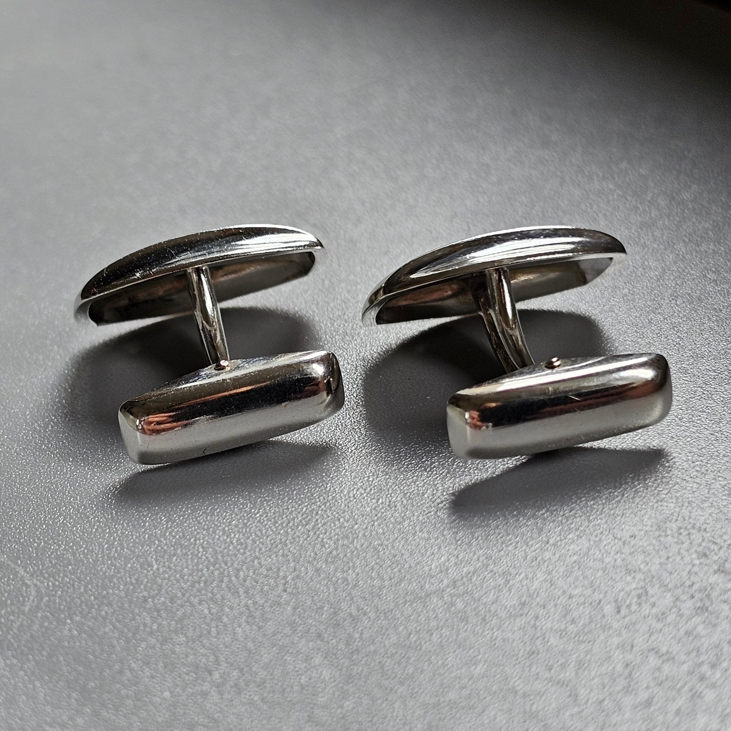 Pair of silver cylindrical cufflinks with rounded ends.