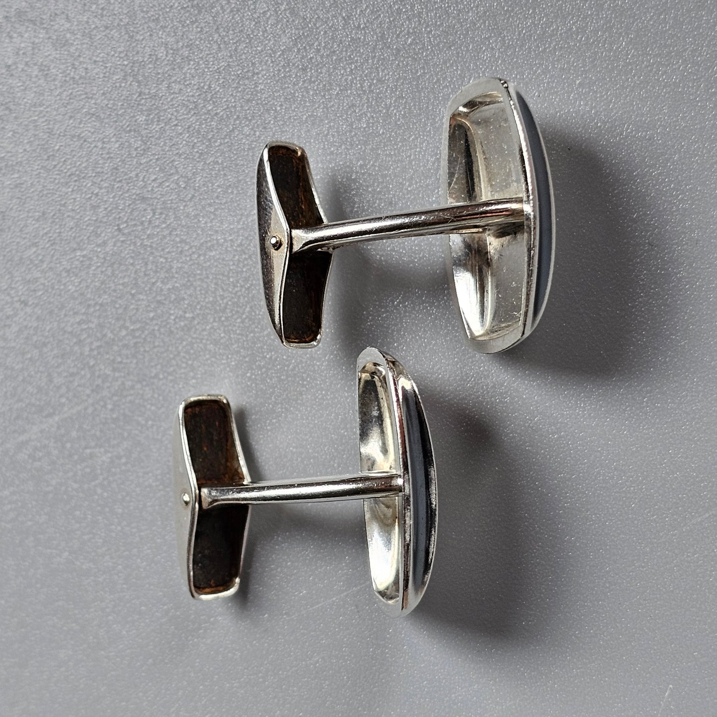 Pair of silver oval cufflinks with T-shaped bars.