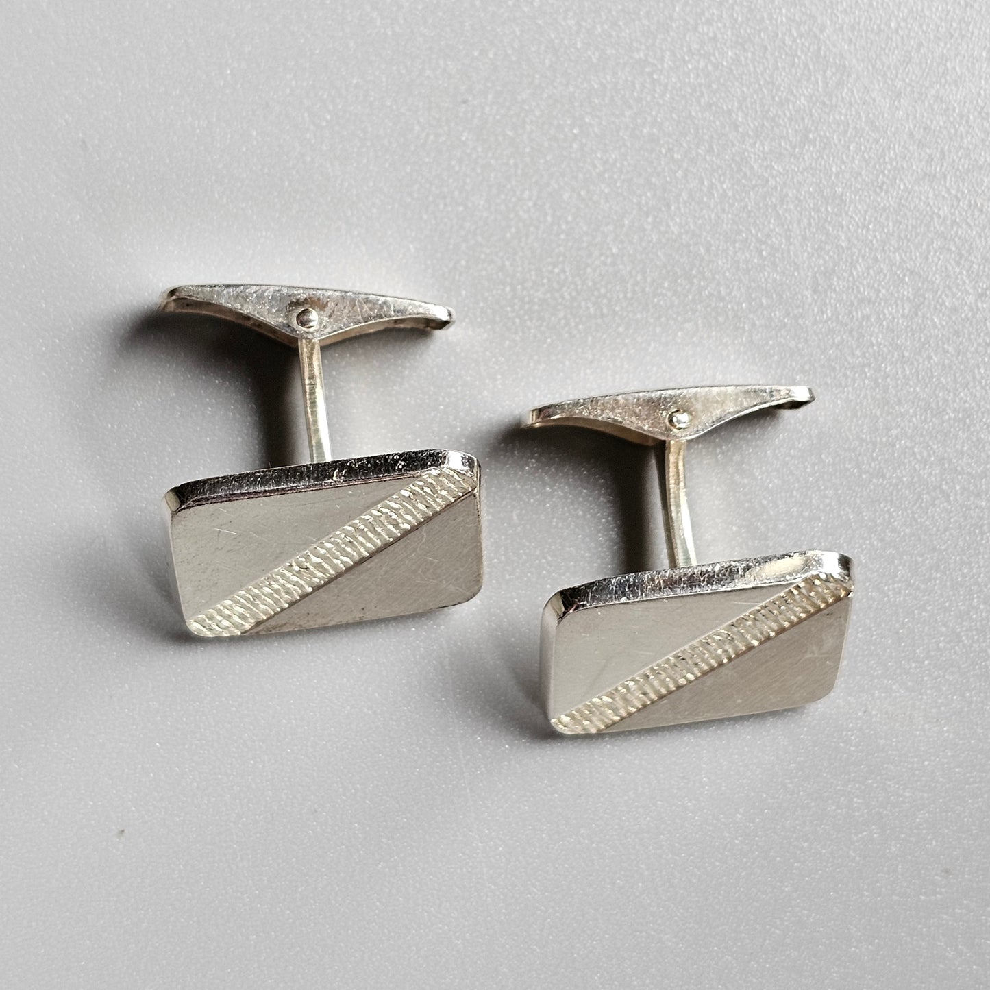 Pair of silver rectangular cufflinks with diagonal textured accents.