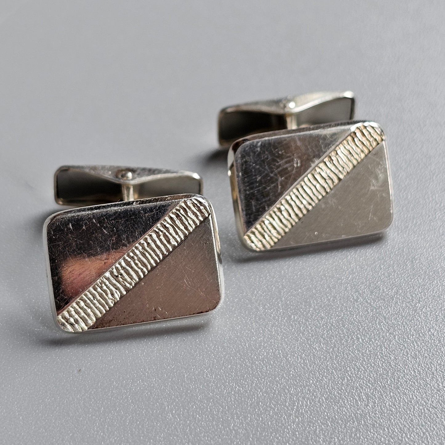 Pair of silver rectangular cufflinks with diagonal textured stripes.