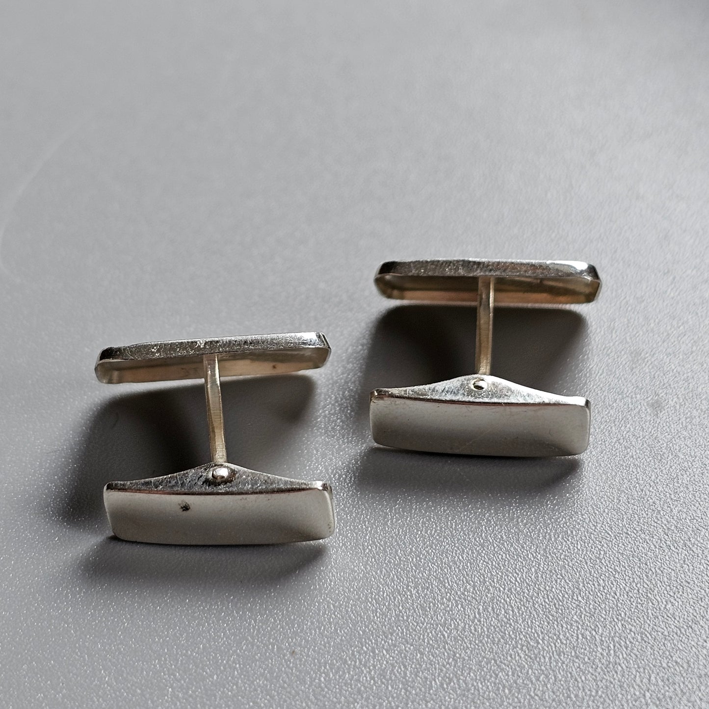 Pair of silver cufflinks with rectangular shapes and connecting bars.