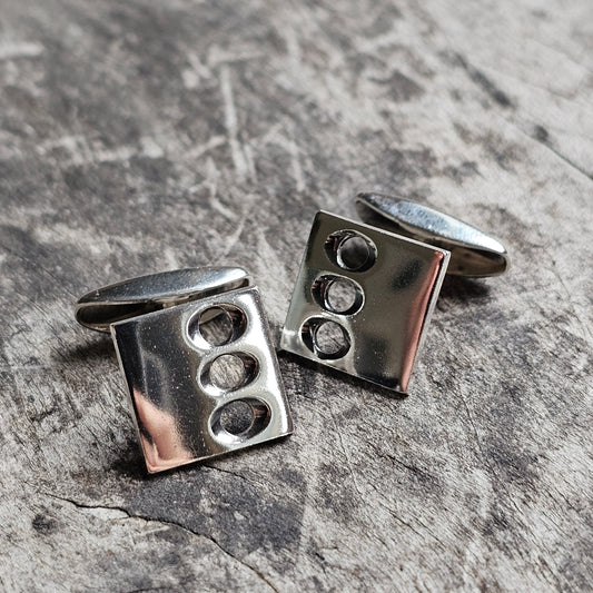 Pair of square silver cufflinks with three circular indentations on each.