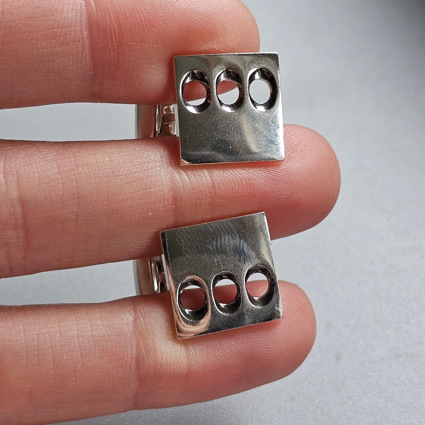 Metal knuckle-style jewelry pieces with three holes each.