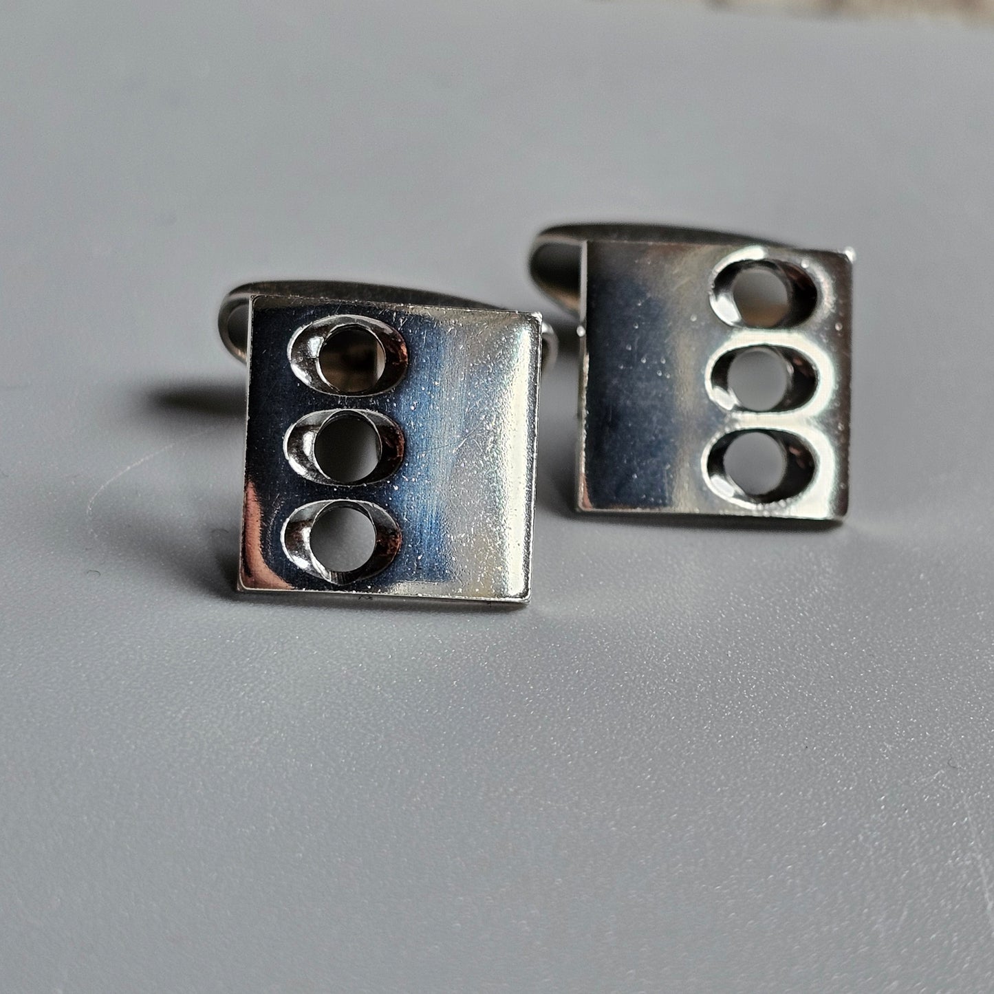 Pair of square silver cufflinks with three oval indentations on each.