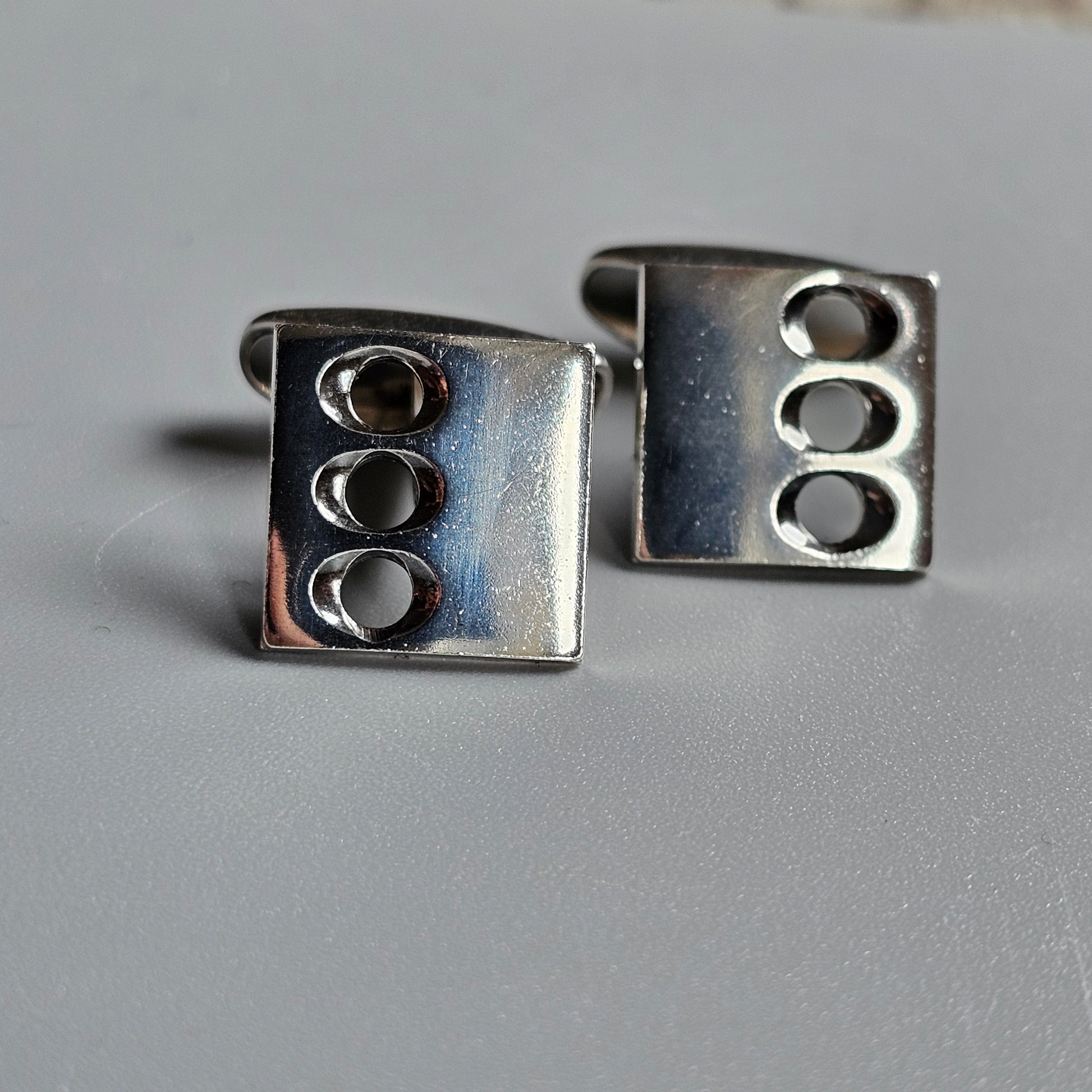 Pair of square silver cufflinks with three oval indentations on each.