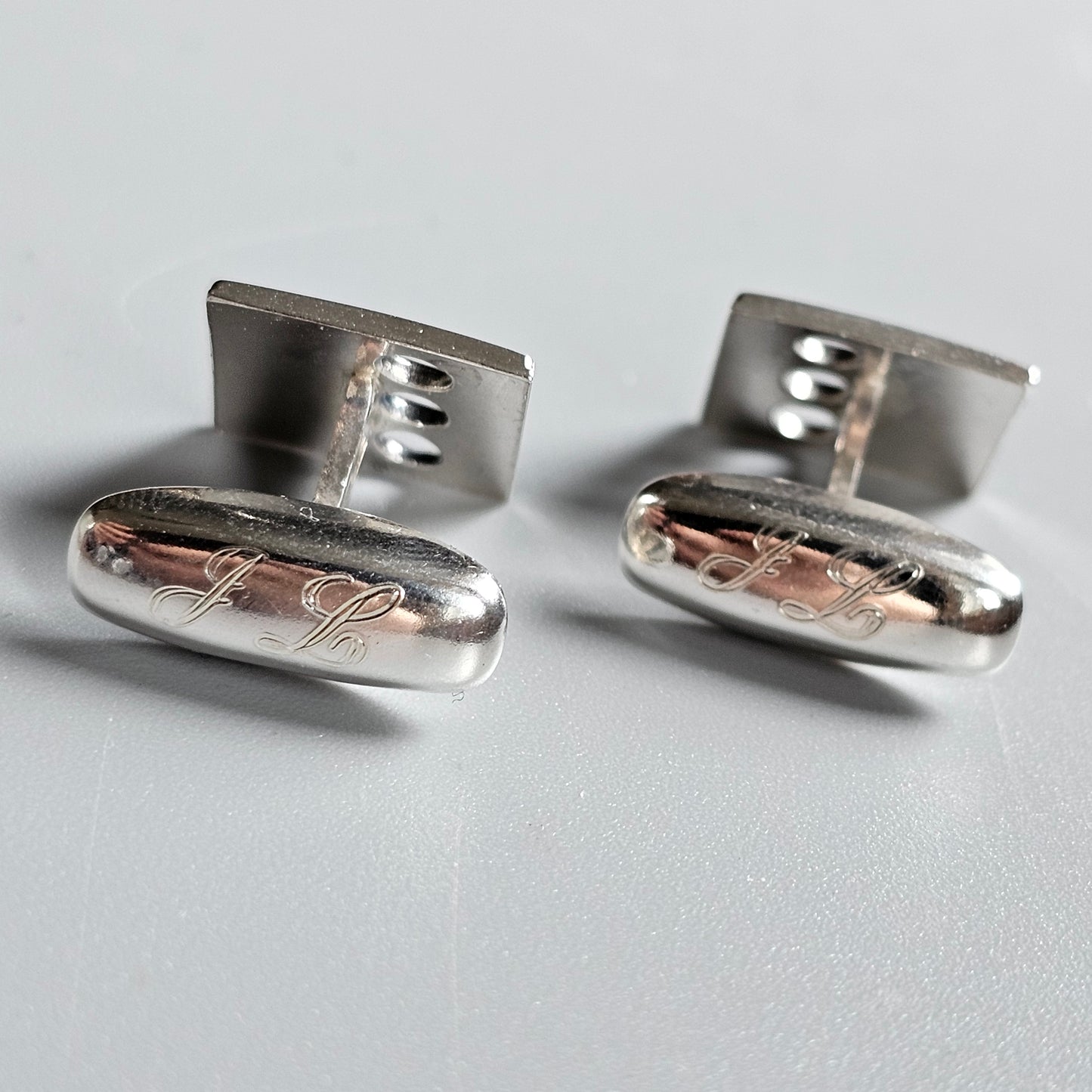 Pair of silver cufflinks with engraved designs.