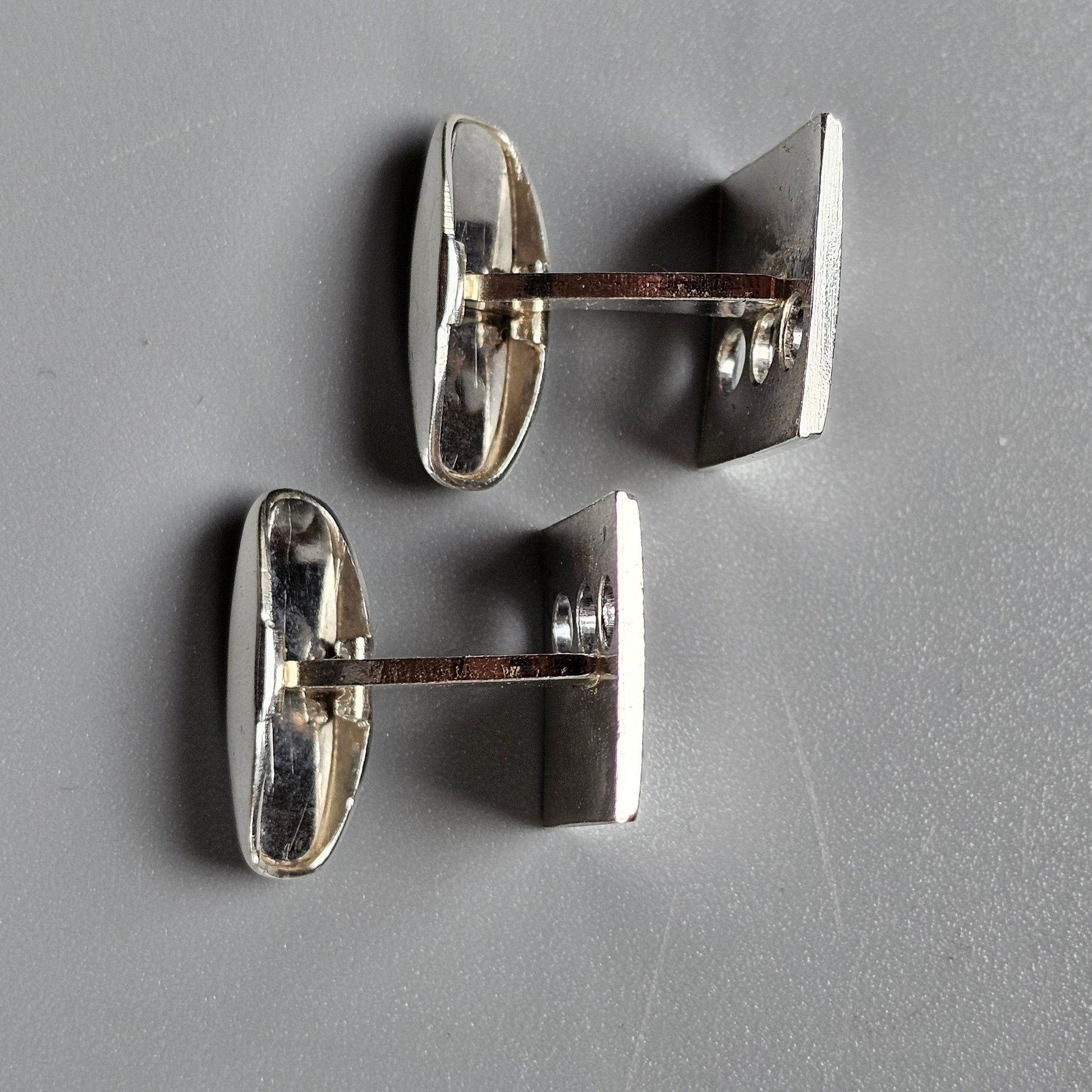 Pair of silver-colored oval cufflinks with visible connecting bars.