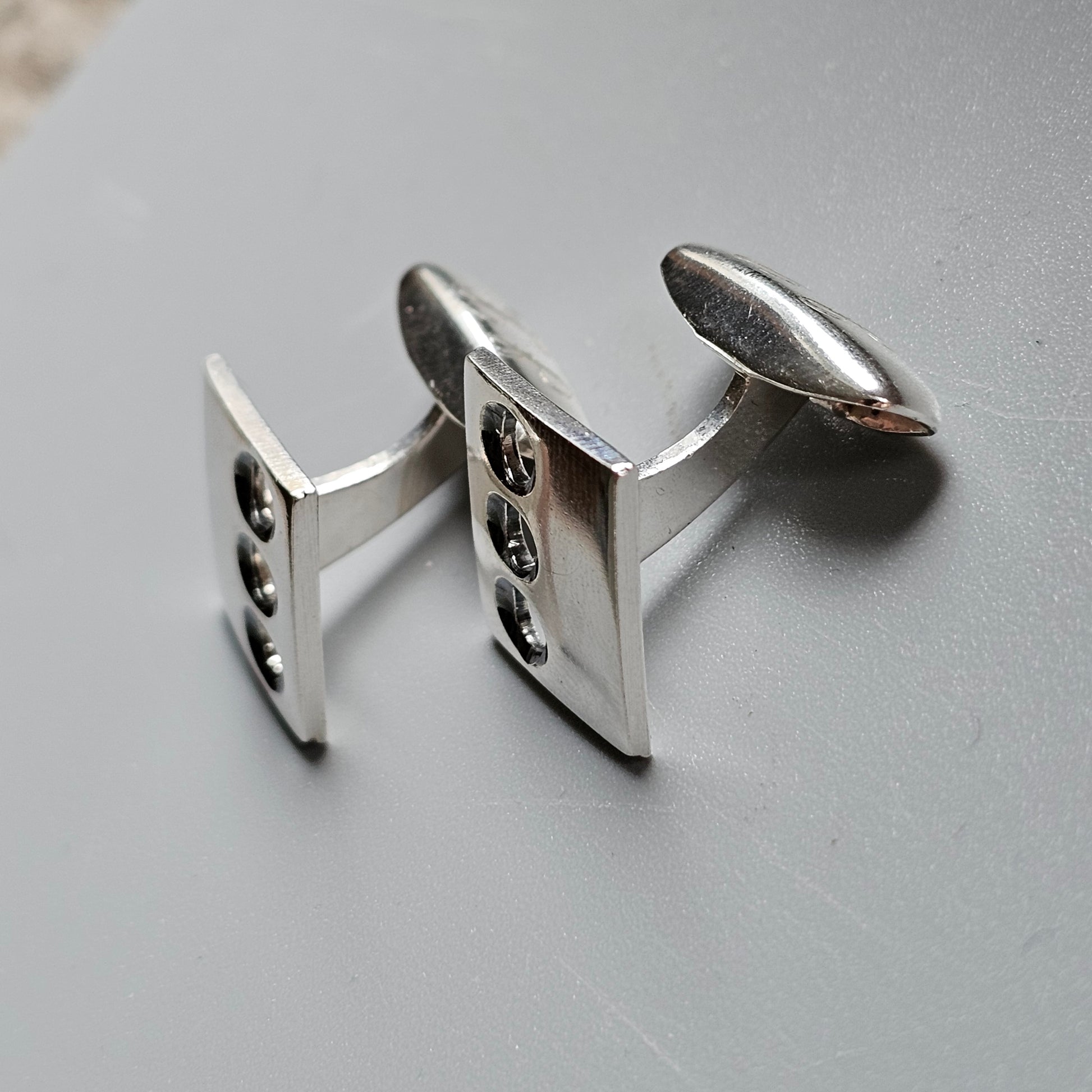 Pair of silver cufflinks with decorative patterns on their faces.