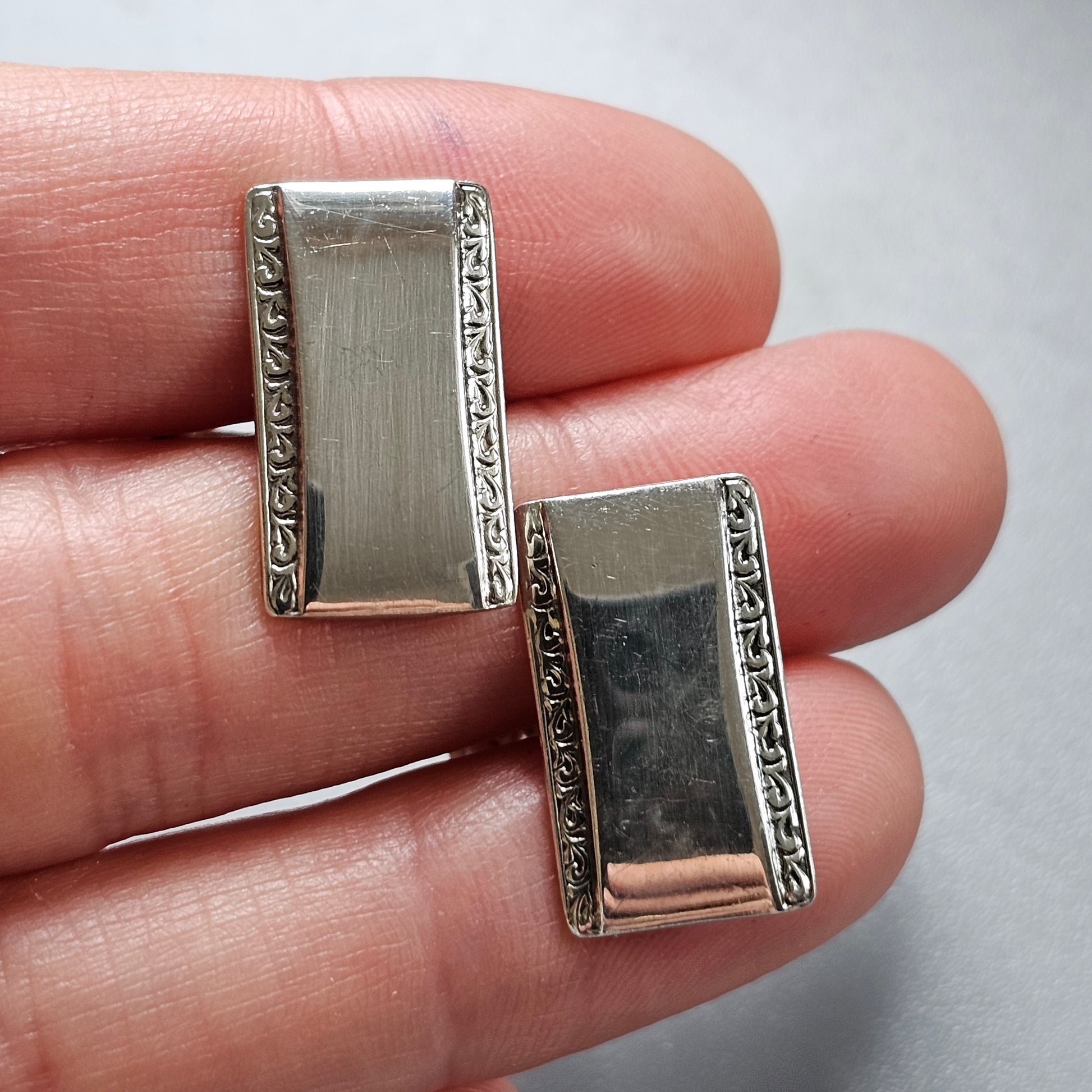 Pair of rectangular silver earrings with decorative borders.