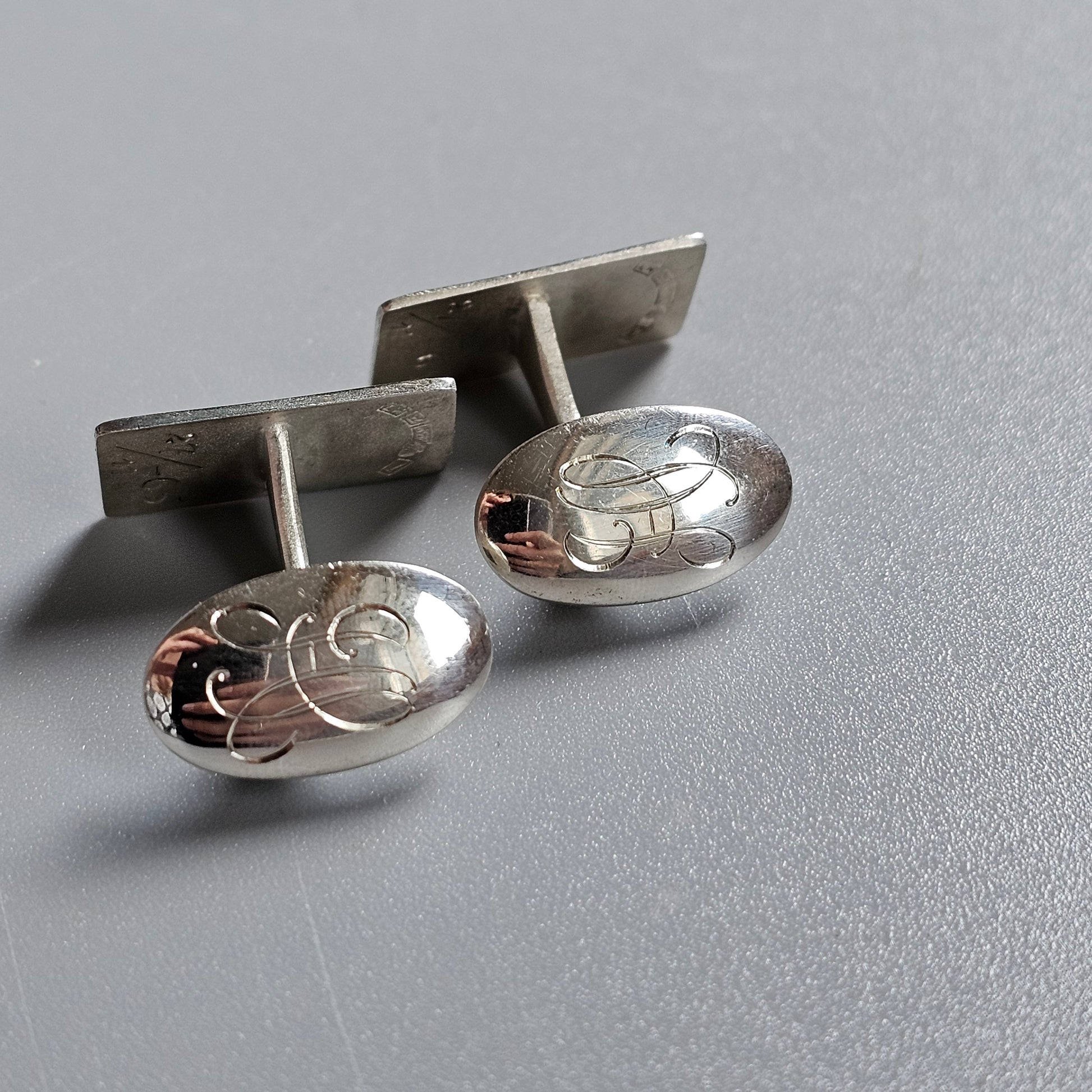 Pair of oval silver cufflinks with engraved floral designs.