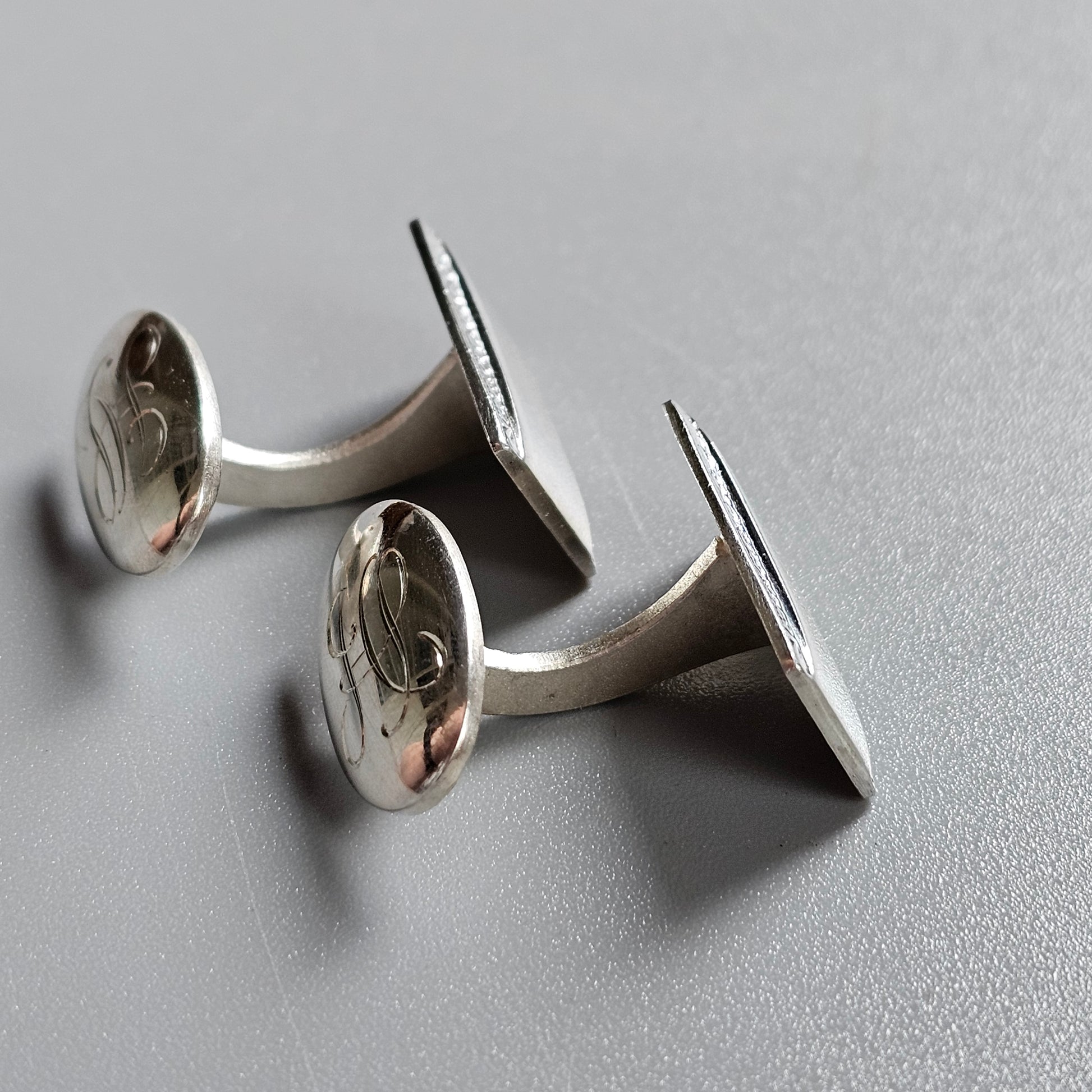 Pair of silver oval cufflinks with engraved designs.