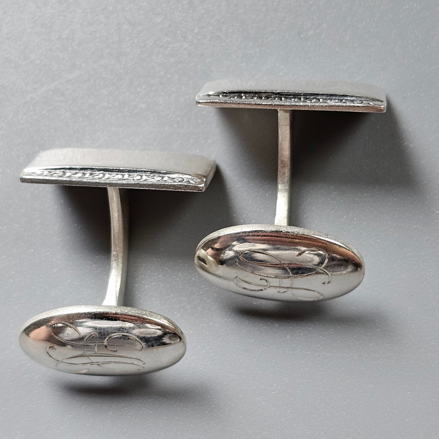 Pair of silver cufflinks with oval bases and rectangular tops.