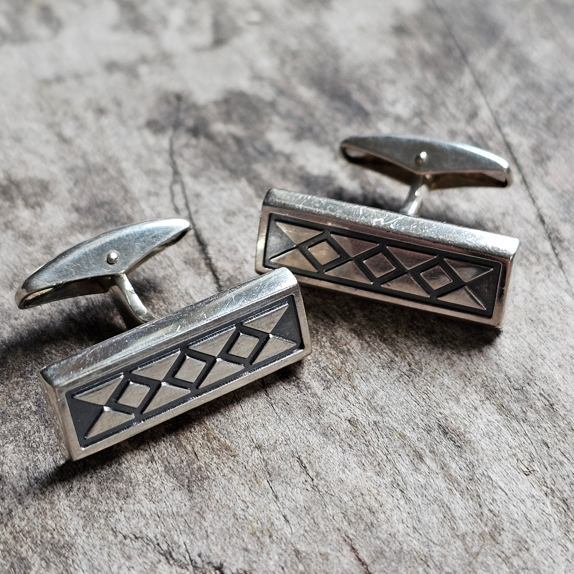 Pair of silver cufflinks with a geometric diamond pattern design.