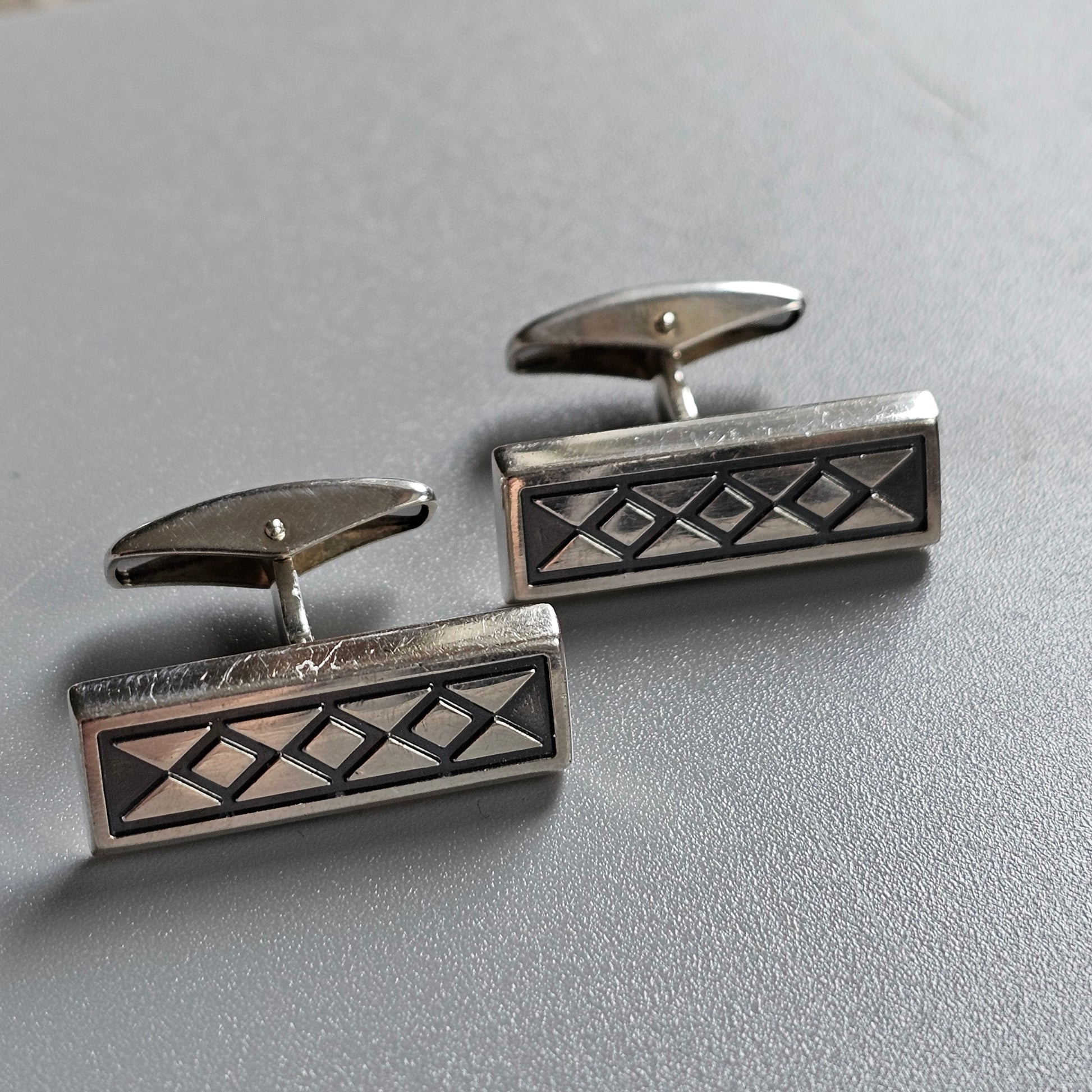 Pair of silver cufflinks with a geometric diamond pattern engraved on rectangular faces.